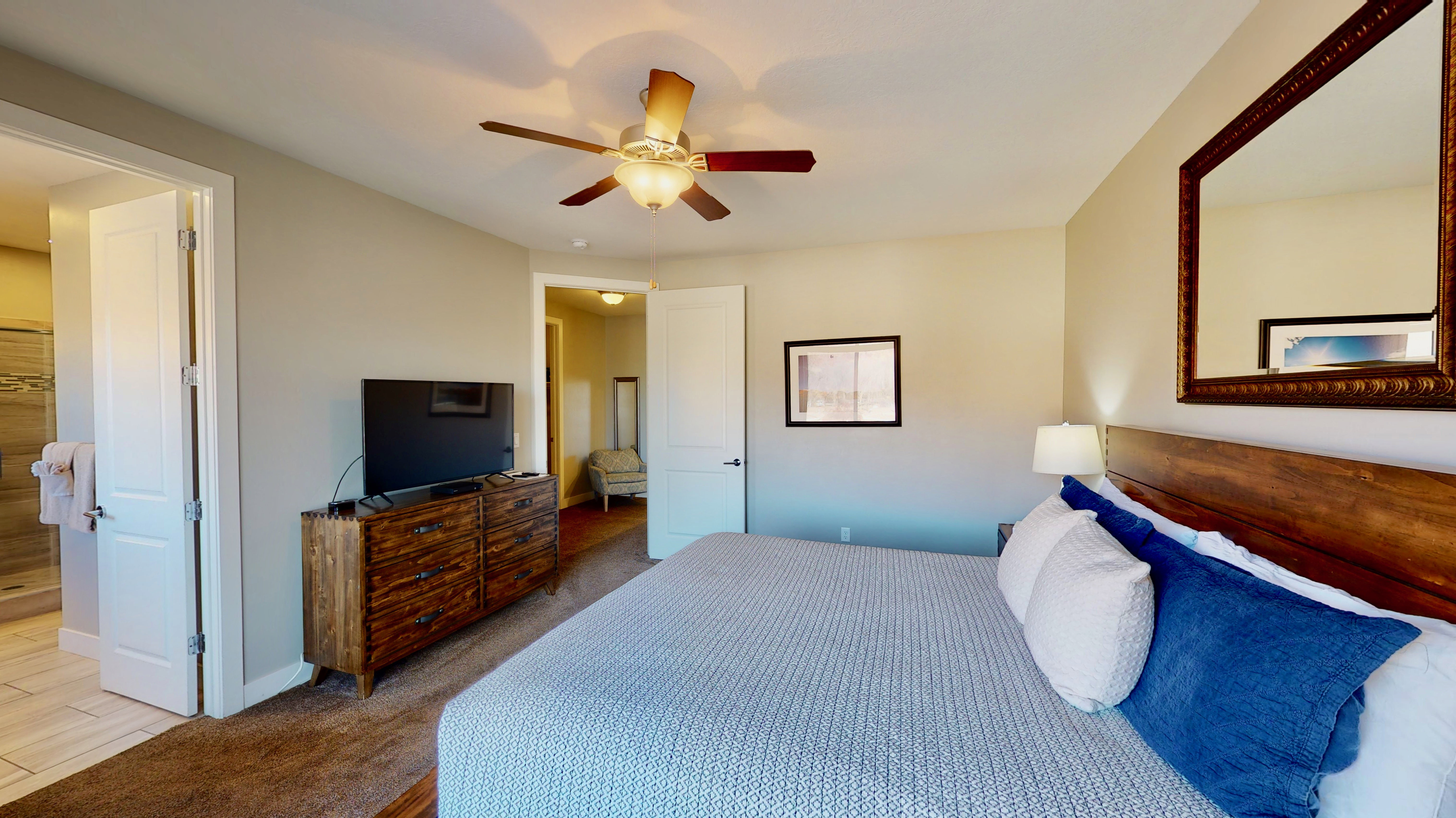 Bedroom featuring neutral wall colors, carpet flooring, a ceiling fan with integrated lighting, and a wood-finish headboard