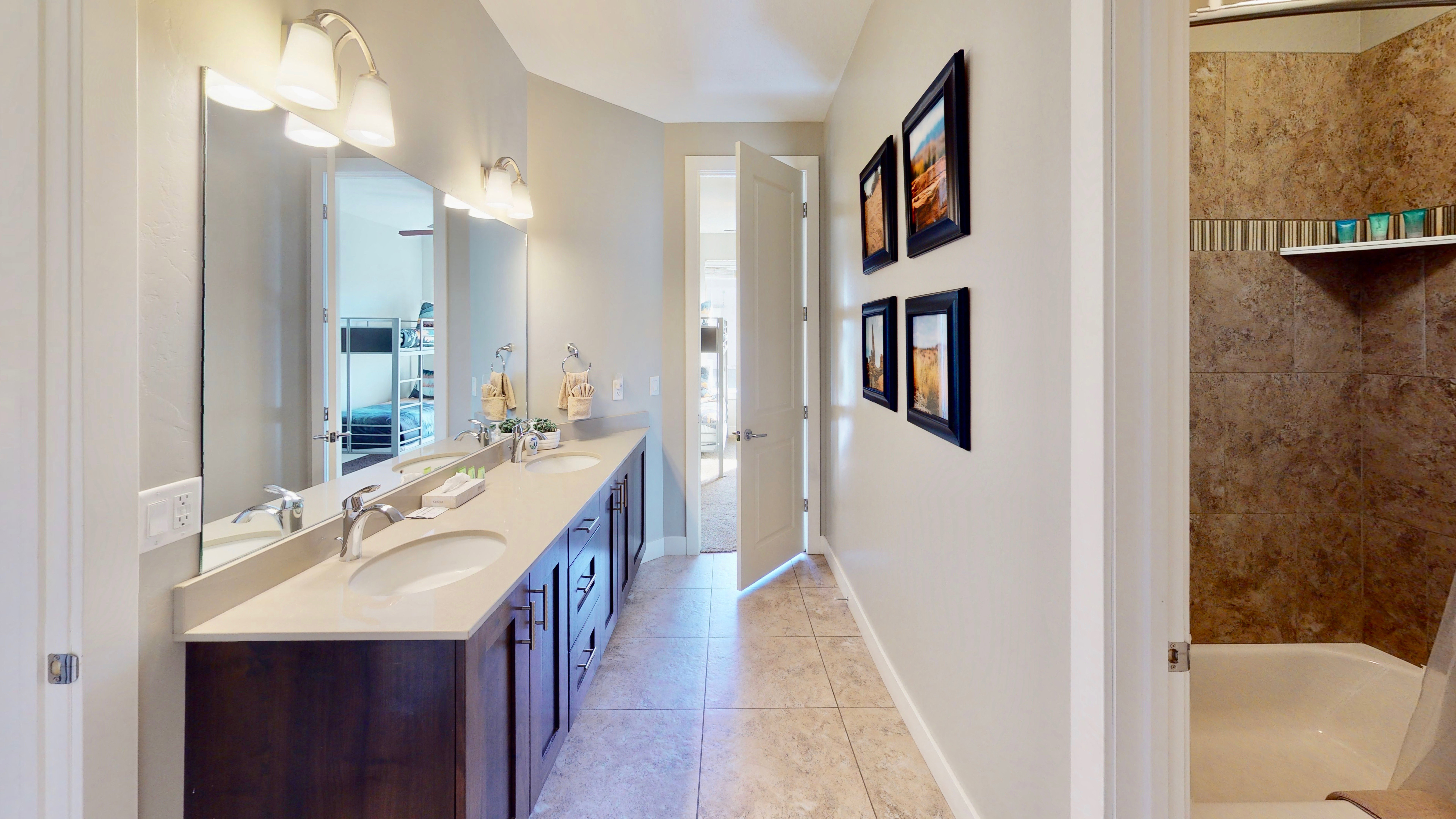 Spacious bathroom featuring a dual vanity with undermount sinks, stone-finish countertop, and dark wood cabinetry