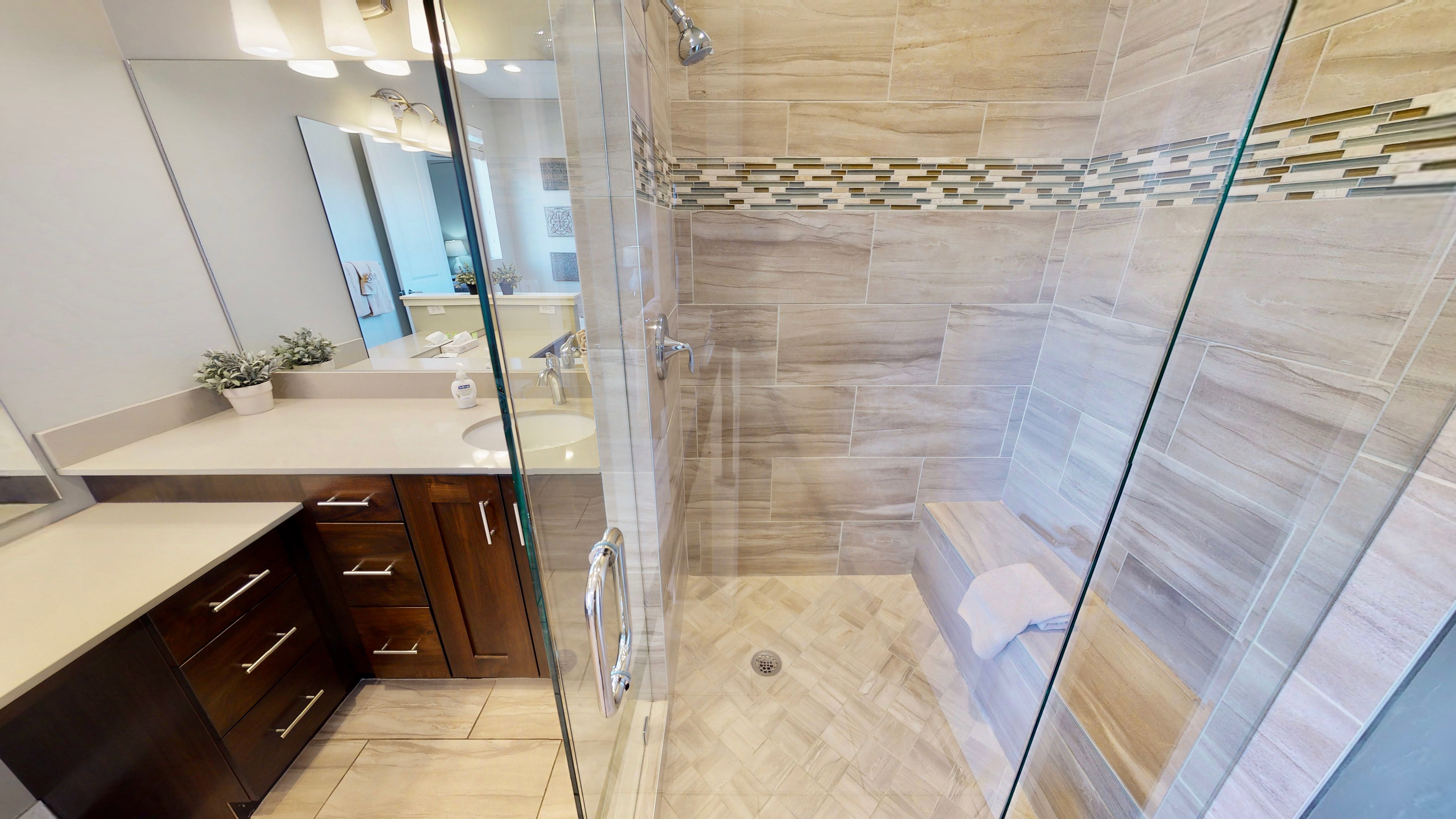 Walk-in shower with glass enclosure, integrated bench, and mosaic accent tile