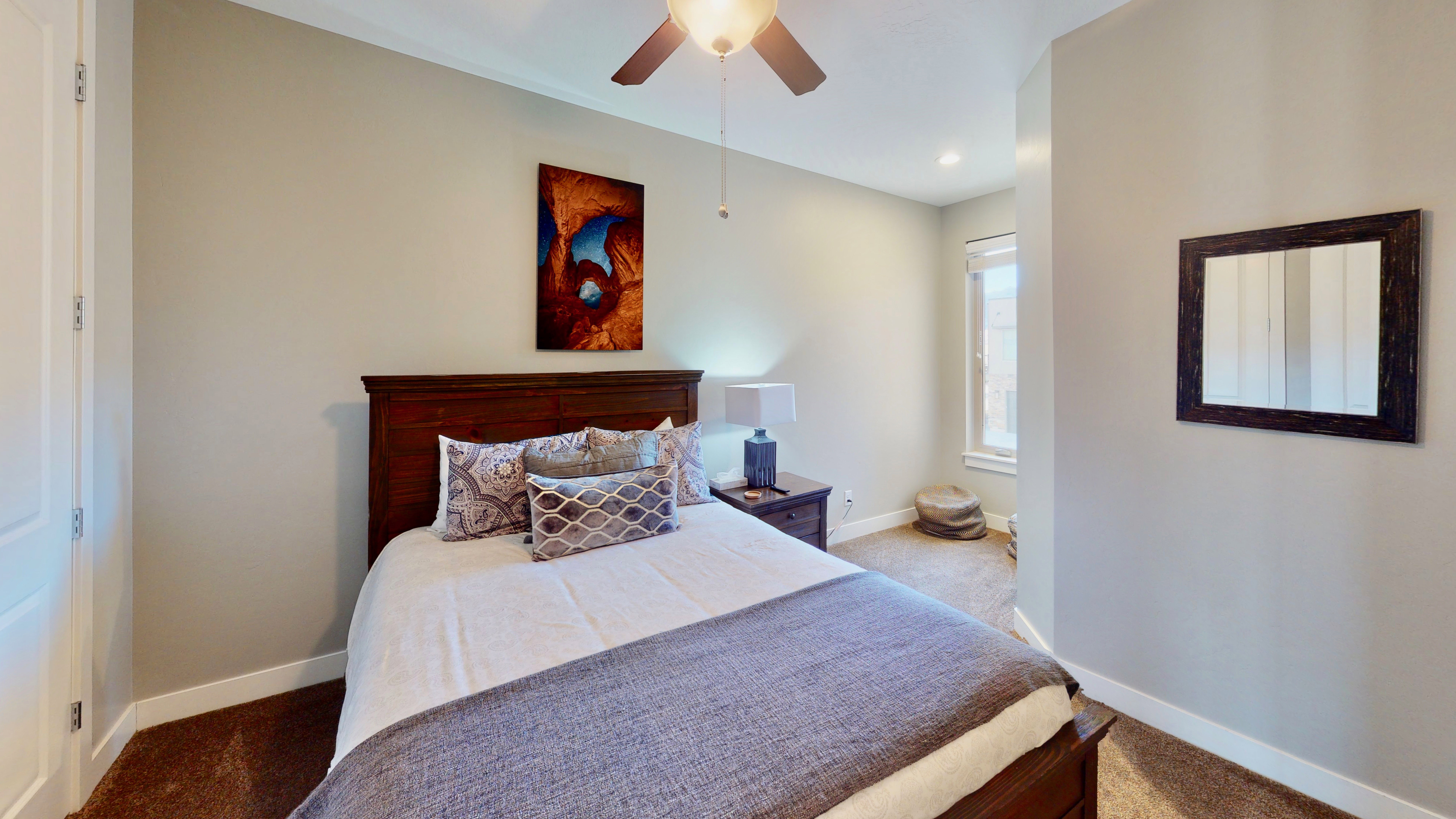 Carpeted bedroom featuring a dark wood bed frame, white trim, and a ceiling fan with integrated lighting