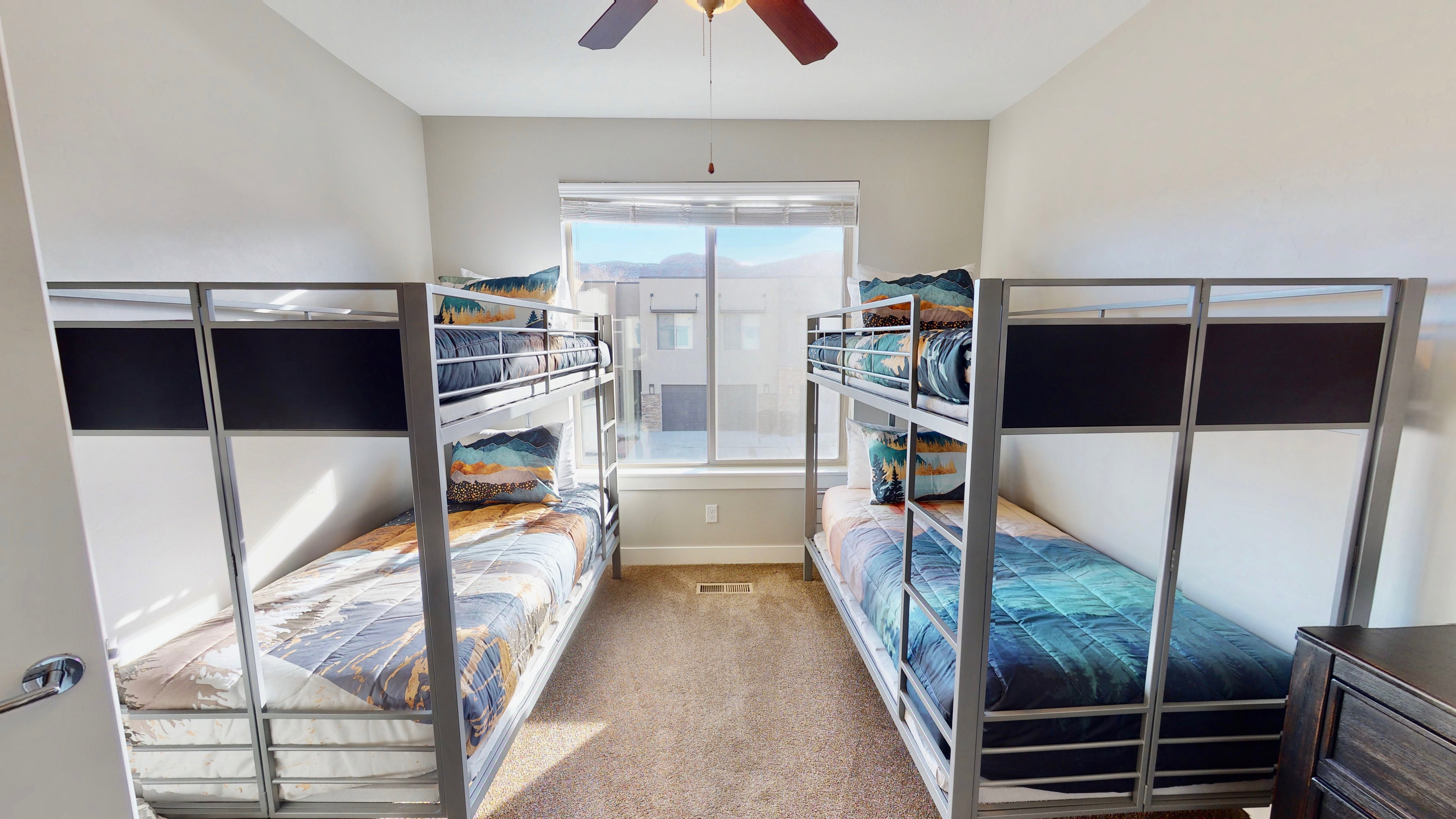 Carpeted room featuring a large window, a ceiling fan, and two built-in bunk bed frames