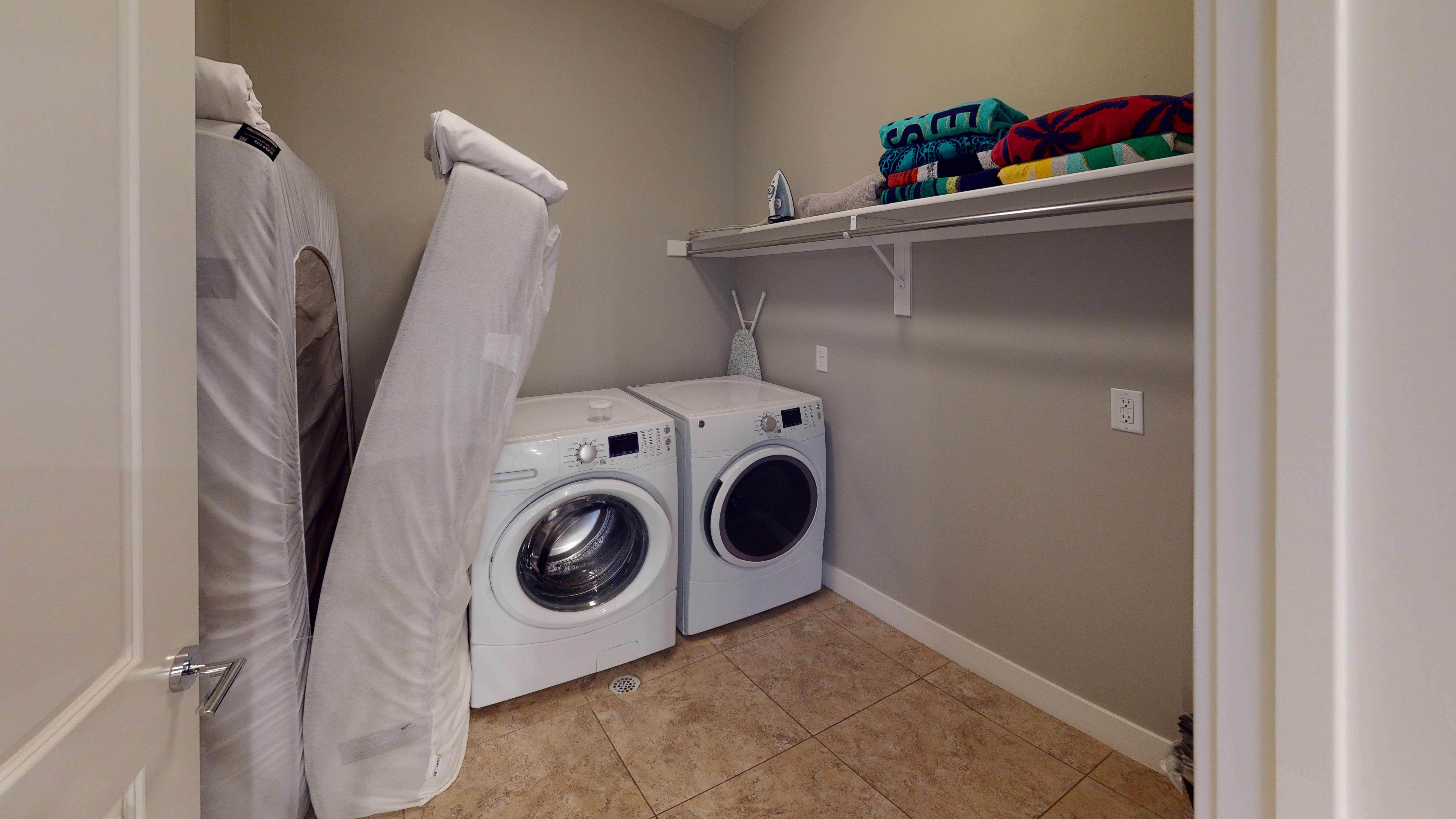 Dedicated laundry area featuring tile flooring, neutral wall paint, and a built-in storage shelf