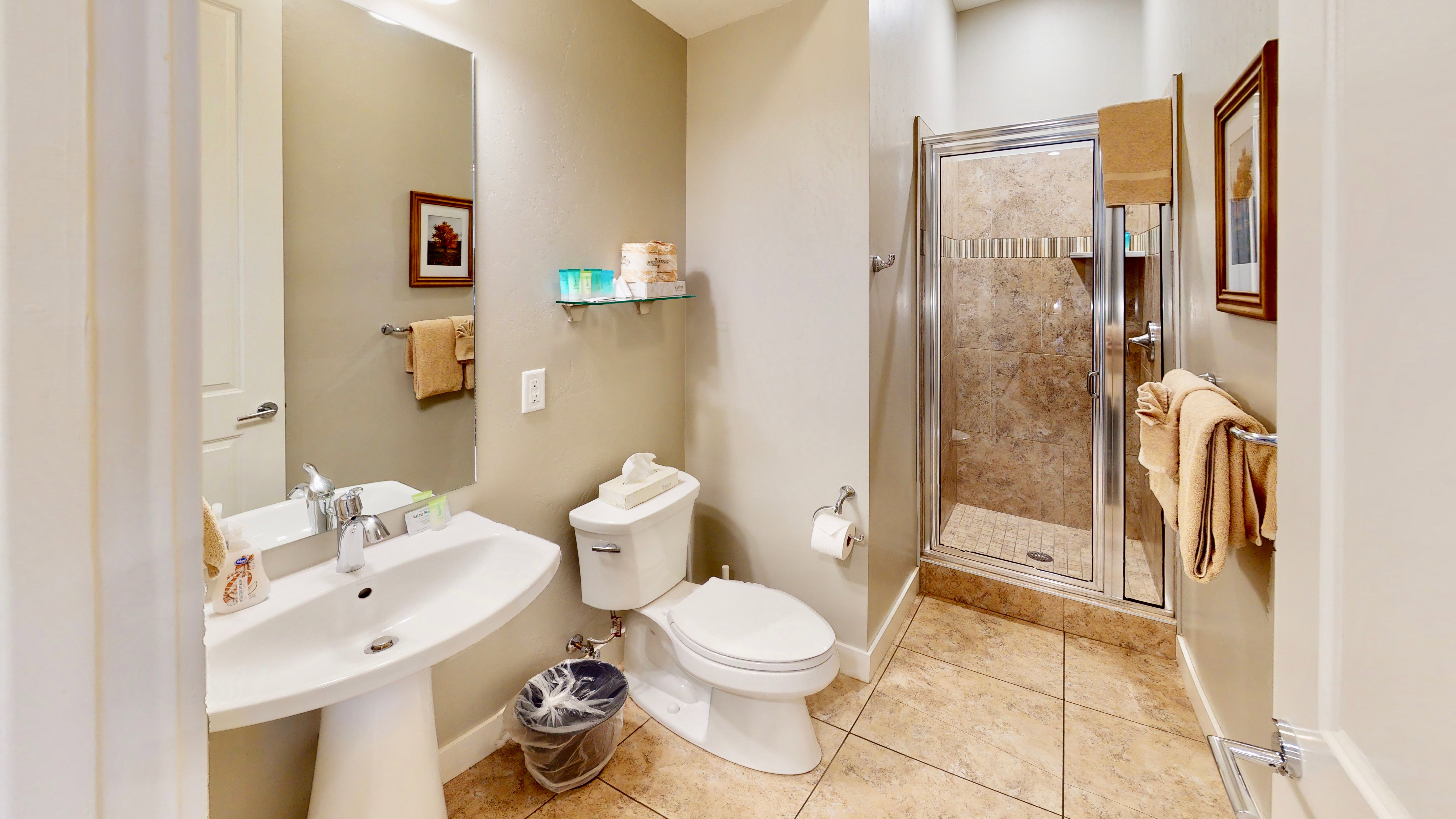 Bathroom featuring a pedestal sink, a frameless mirror, a glass-enclosed shower with tiled walls, neutral-toned wall paint, and square tile flooring