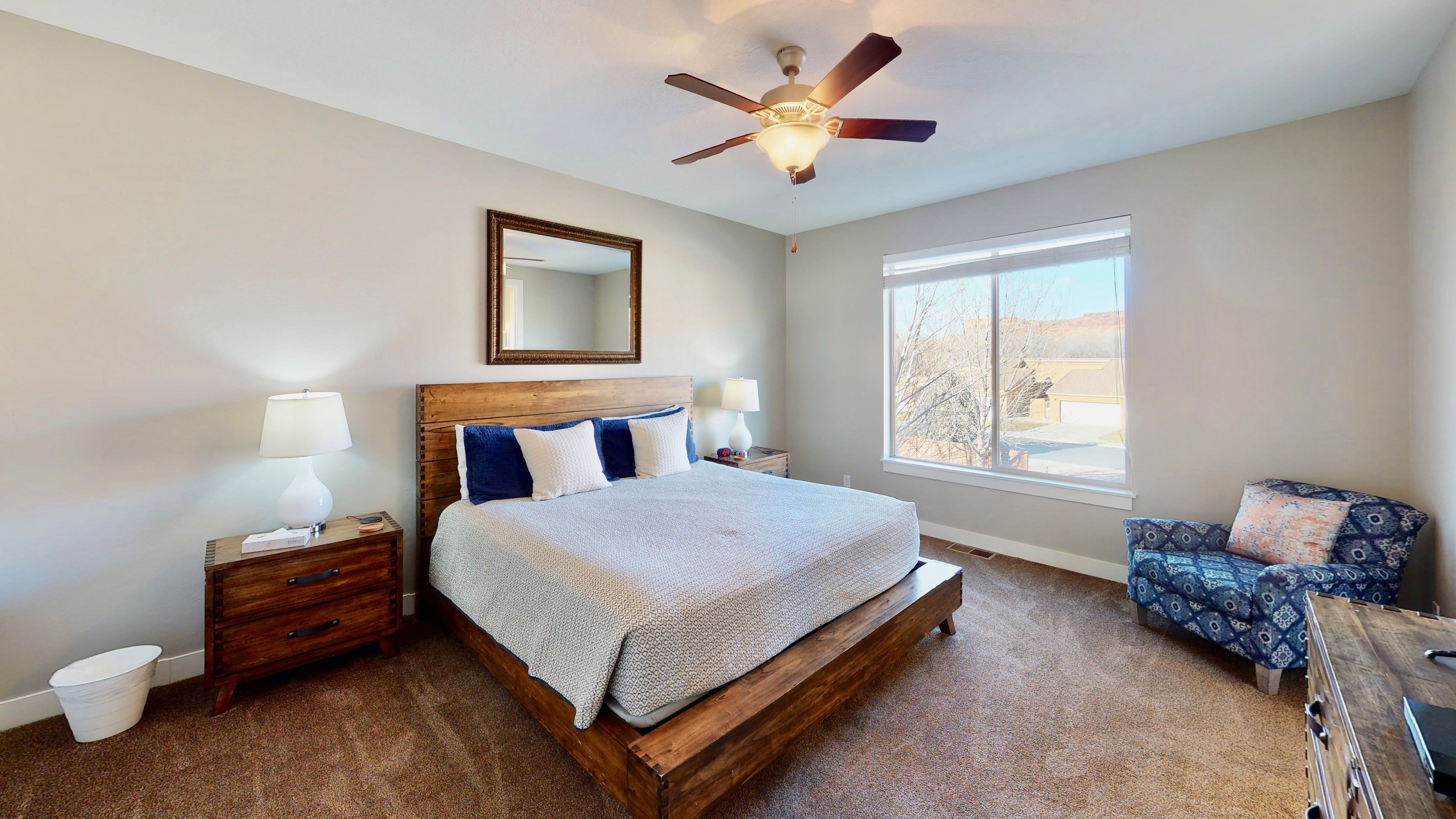 Carpeted room featuring a ceiling fan with integrated lighting, a large window with natural light, and neutral wall tones