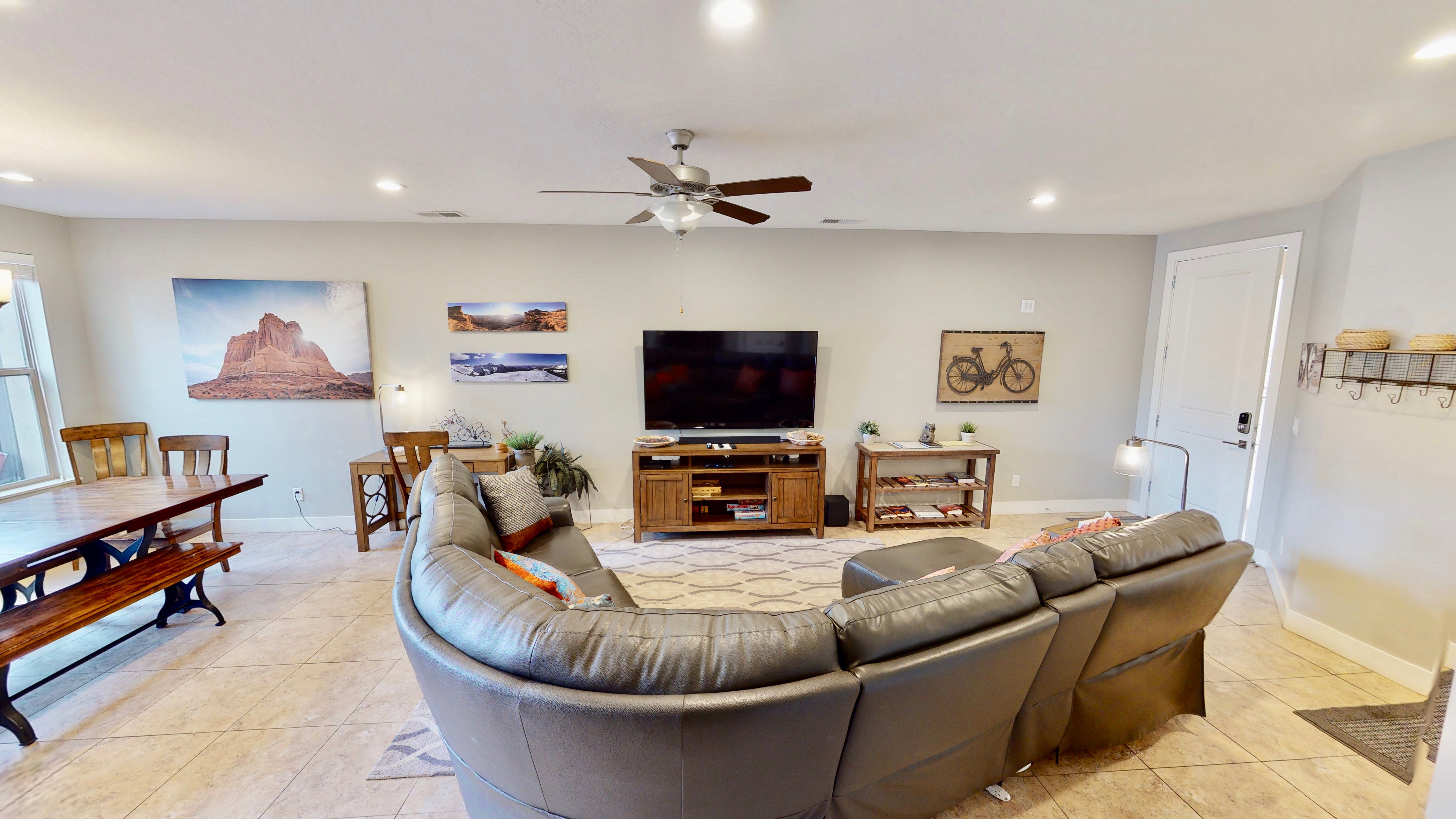 Open-concept living space featuring neutral wall tones, recessed lighting, a ceiling fan, and large tile flooring