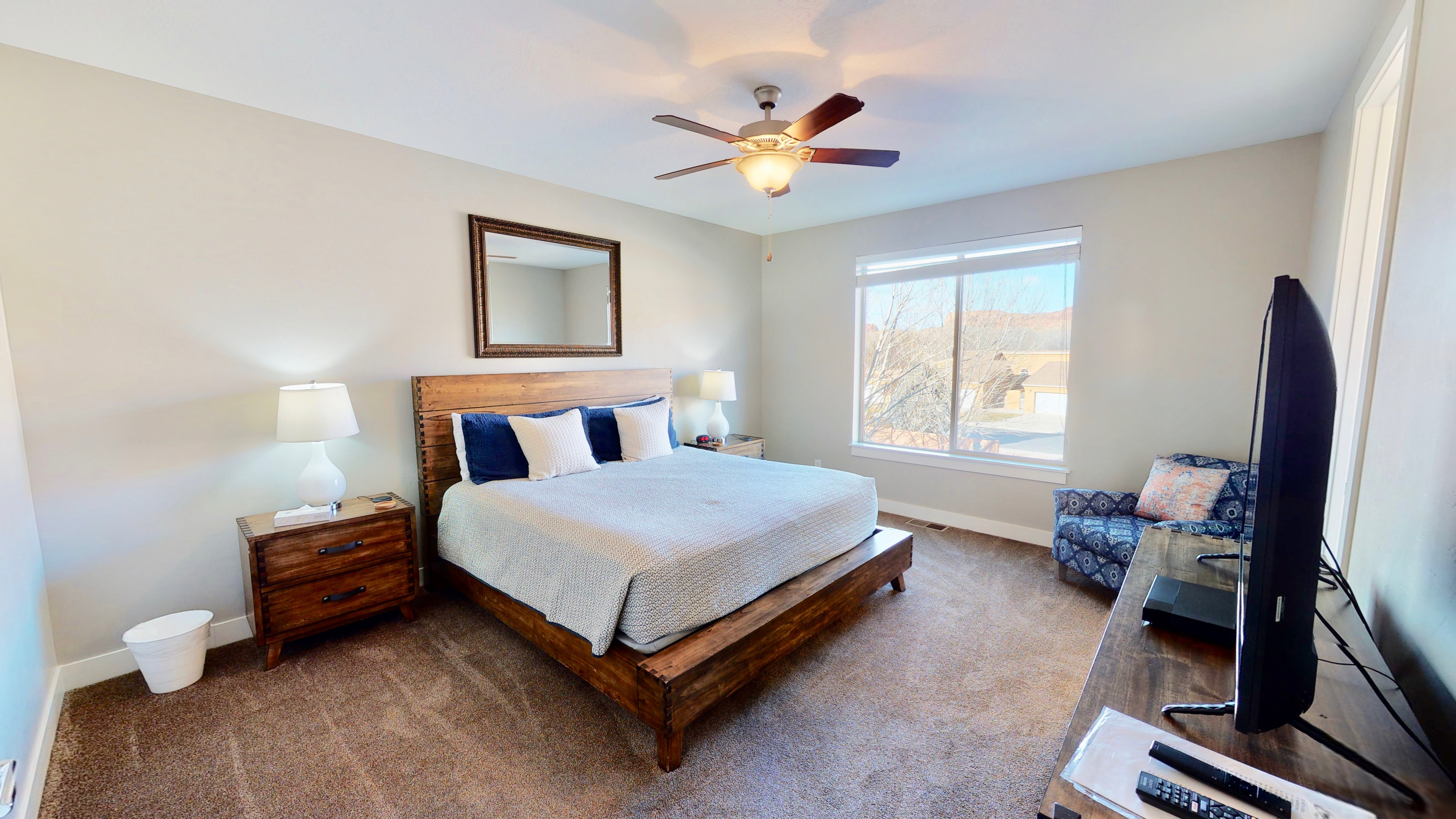 Carpeted room featuring a ceiling fan with integrated lighting, a large window with white trim, and light-colored walls
