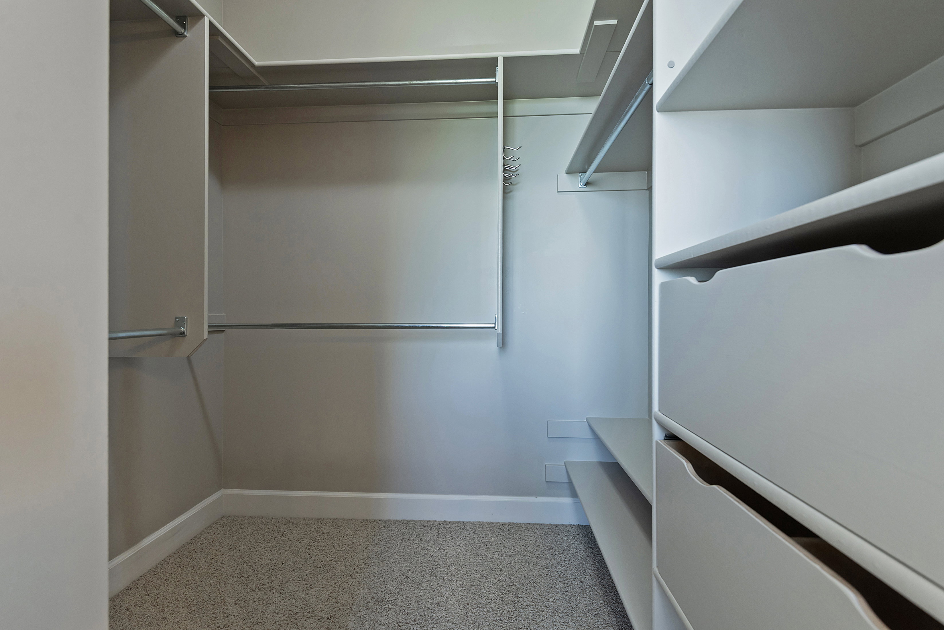Built-in custom closet system featuring multiple hanging rods, integrated shelving, and dedicated drawer storage