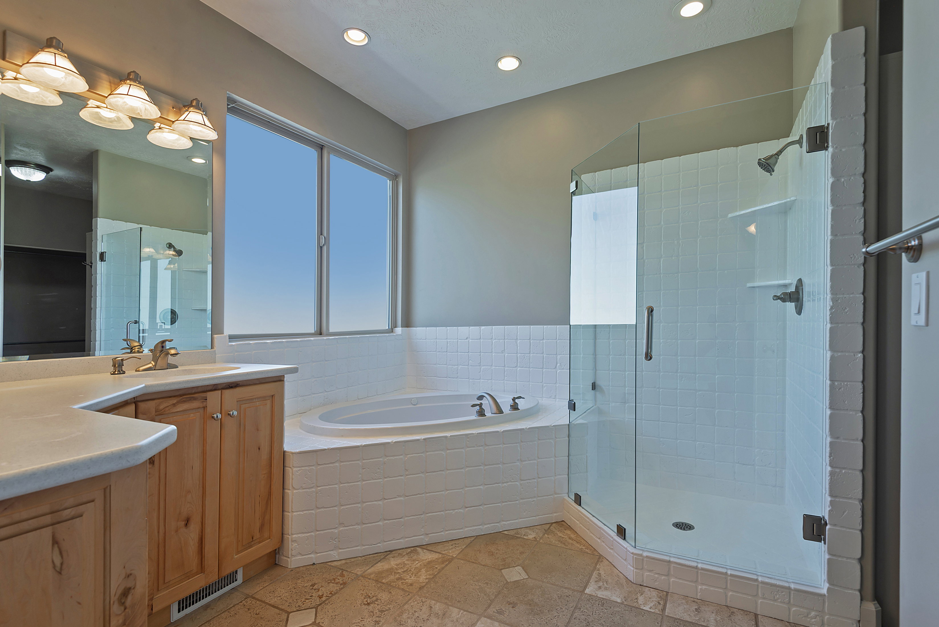 Bathroom featuring a glass-enclosed shower, a built-in jetted tub, and a vanity with wood cabinetry