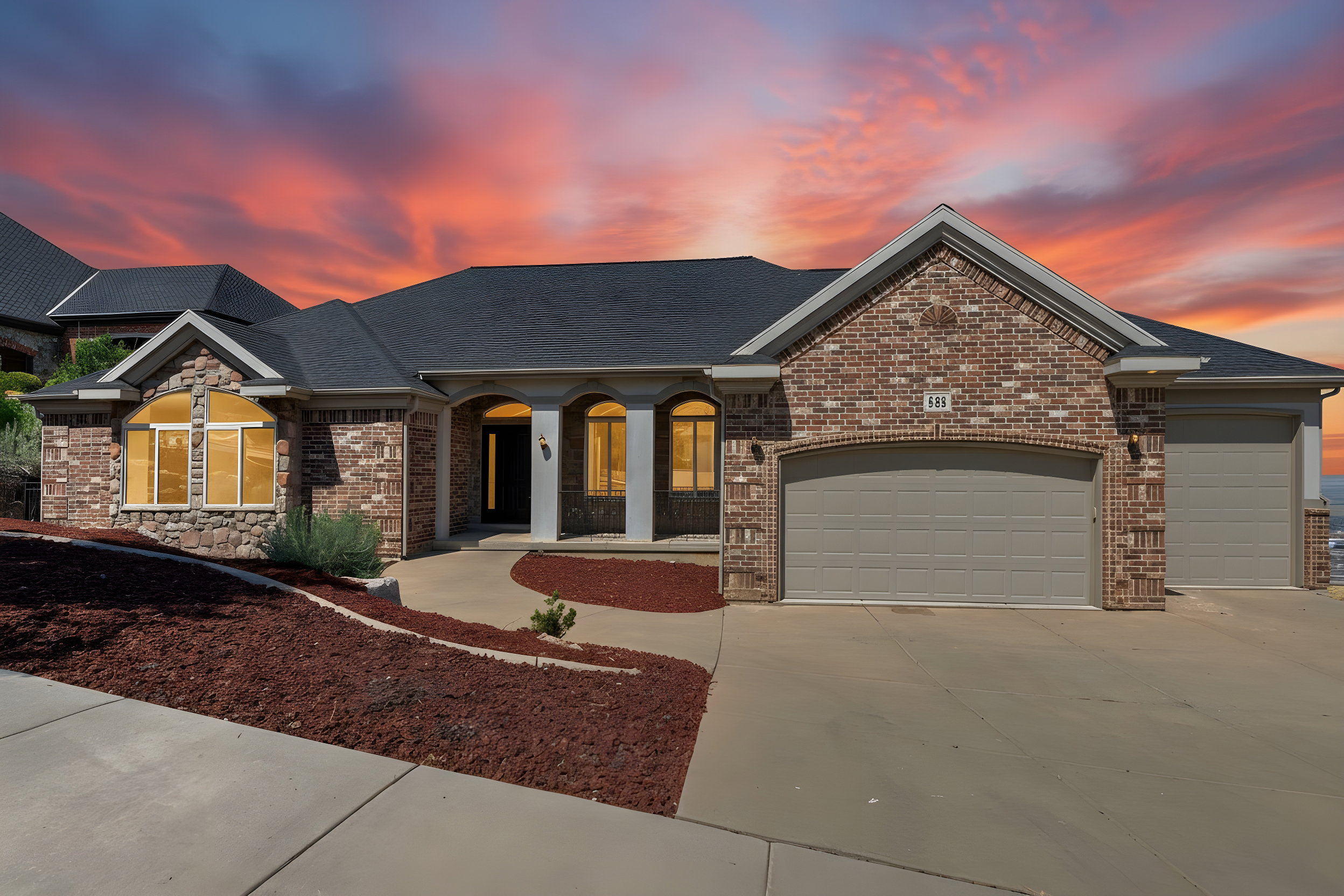 Brick and stone facade residence featuring a covered entry, arched window detail, and a two-car garage