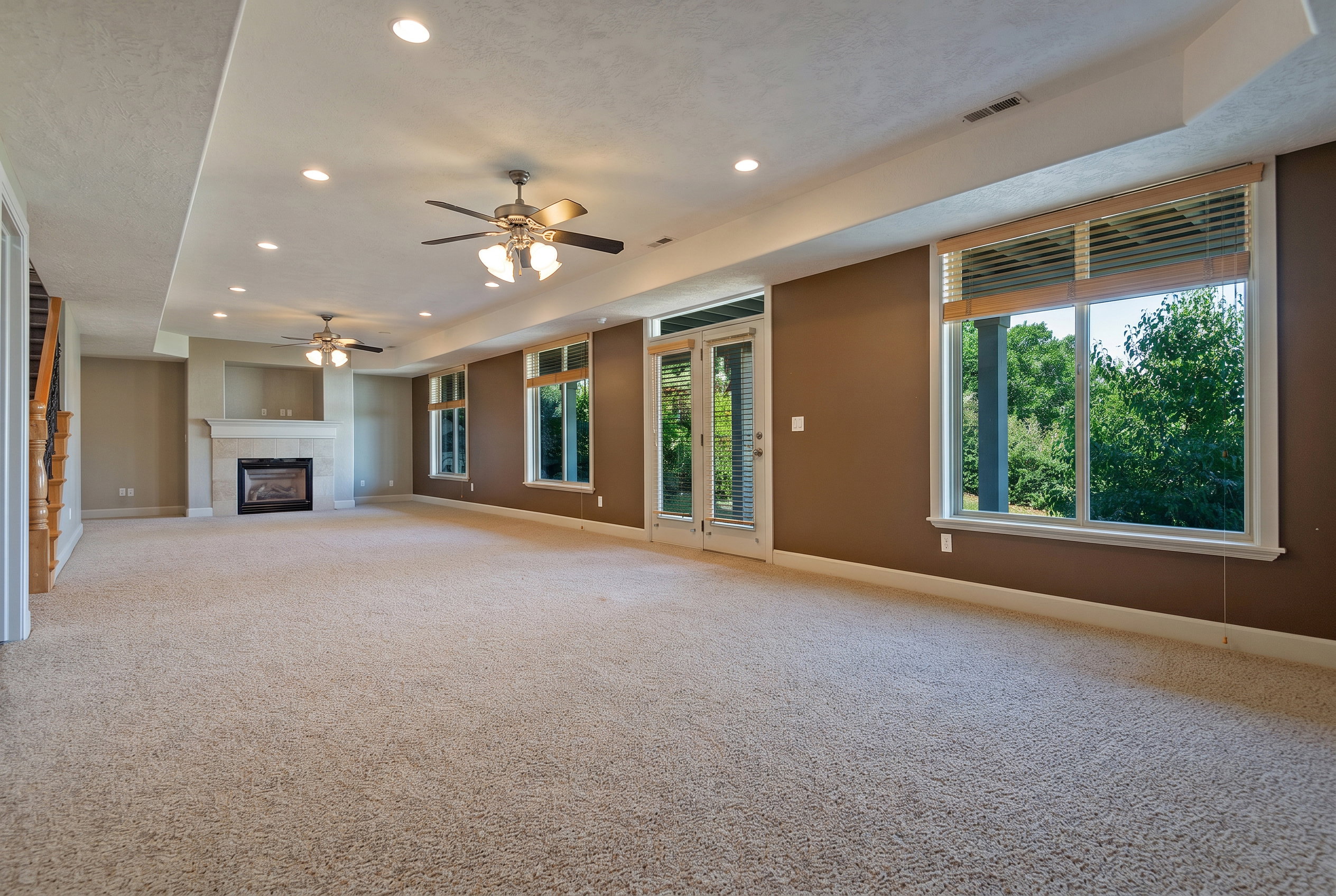 Spacious recreation room featuring neutral carpeting, recessed lighting, and a stone-clad fireplace with mantel