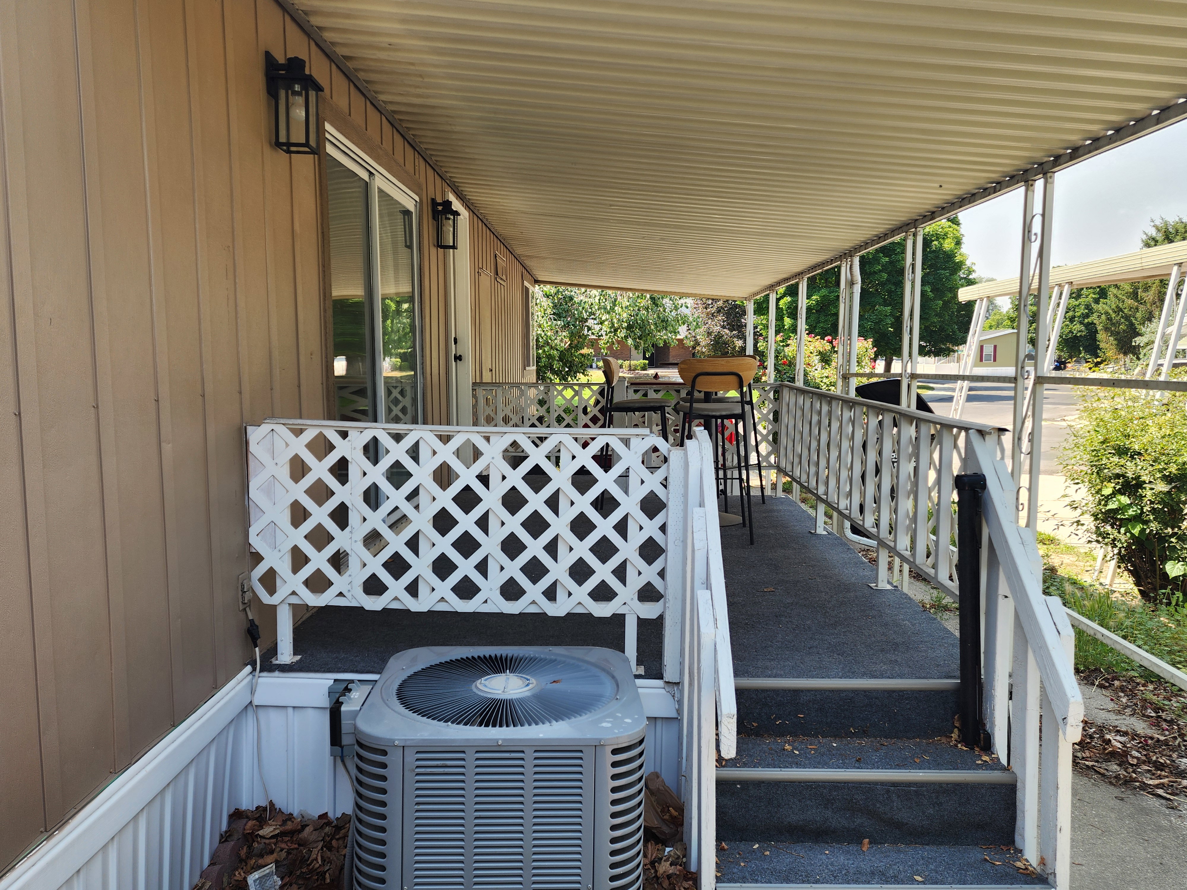 Covered porch with outdoor carpeting and white lattice railing