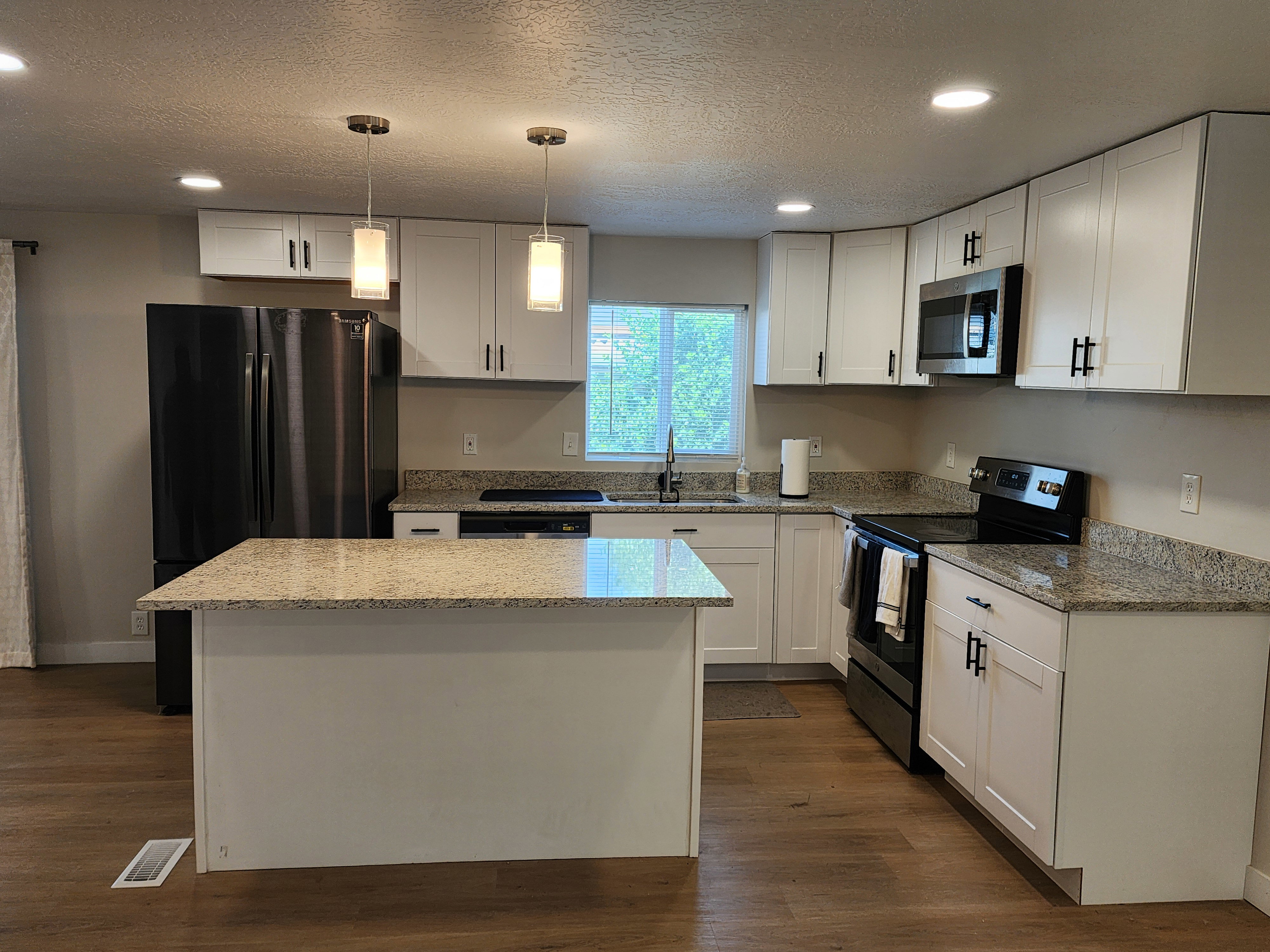Kitchen featuring white cabinetry, granite countertops, wood-finish flooring, a stainless steel sink, and recessed lighting
