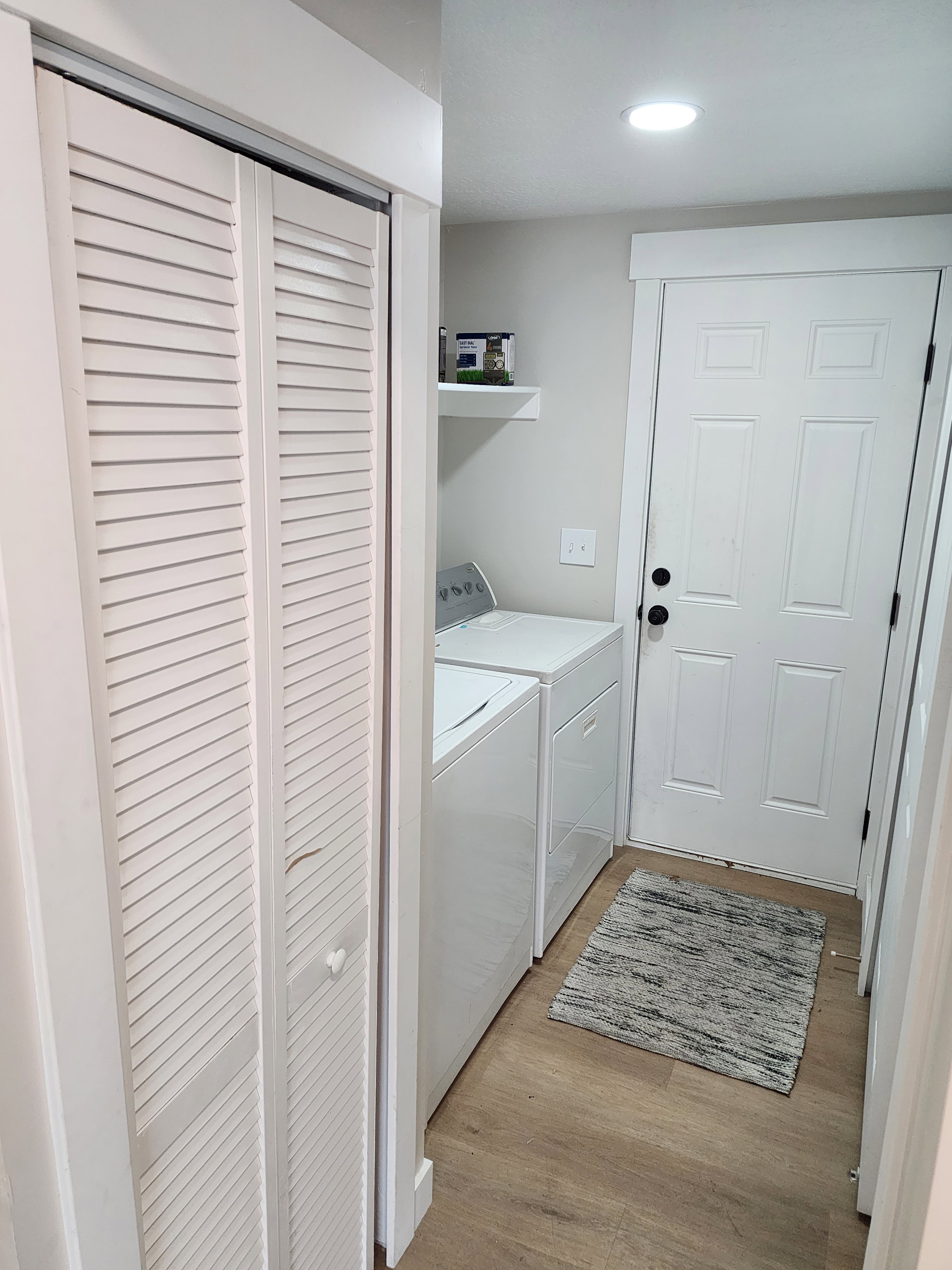 Dedicated laundry area featuring wood-finish flooring, recessed lighting, a floating shelf, and louvered bifold closet doors