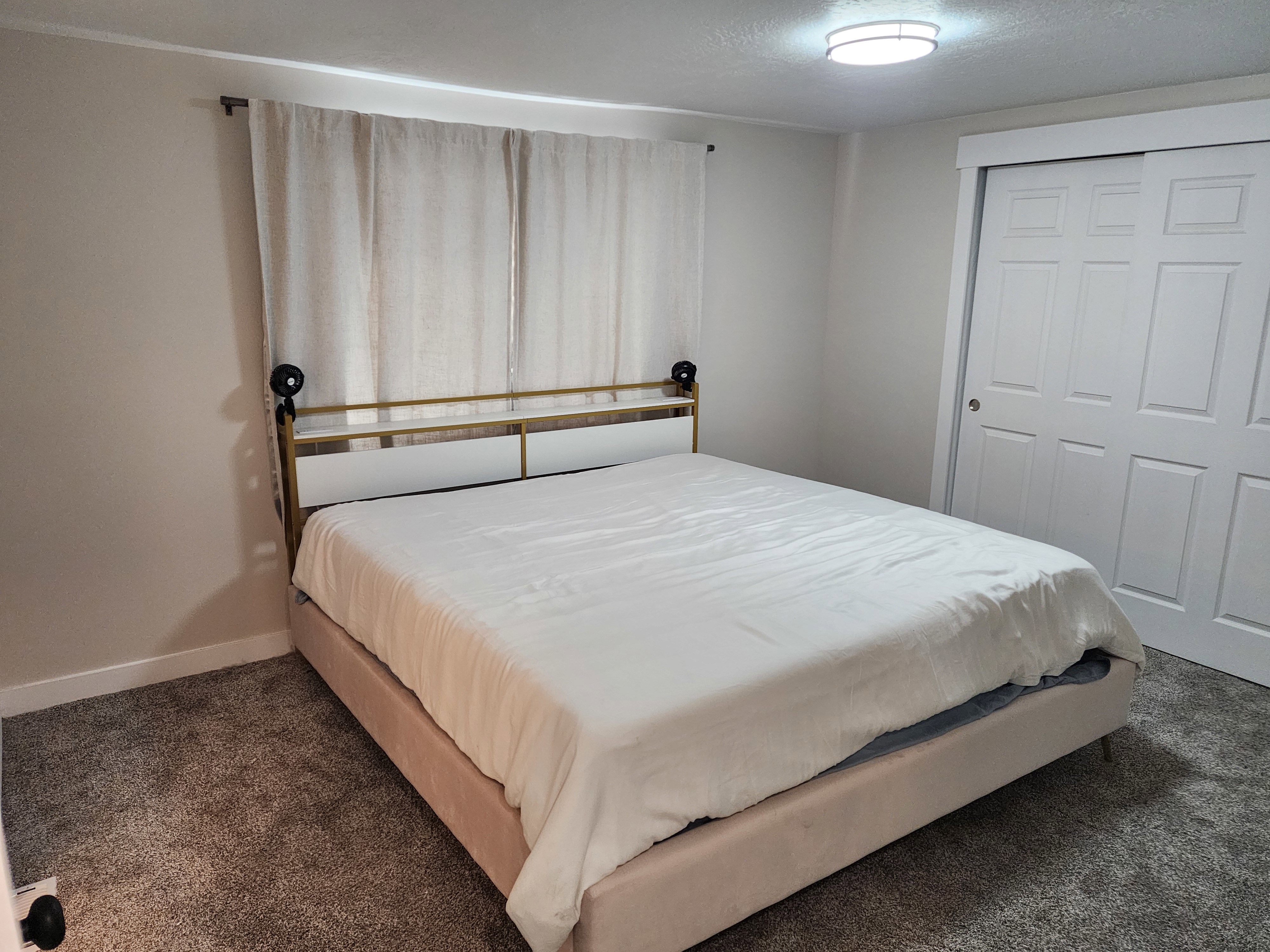 Wall-to-wall carpeting and neutral wall tones define this room, featuring a double-door closet with panel detailing and a flush-mount ceiling light fixture