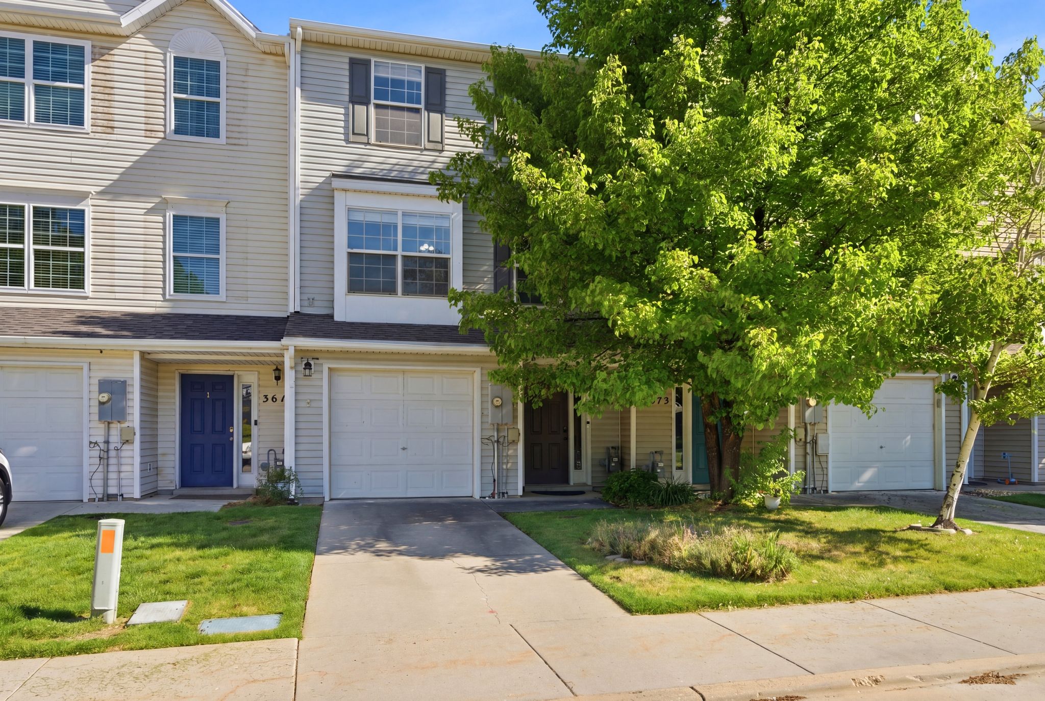 Two-story townhouse exterior with light siding, a single-car garage, and a front porch
