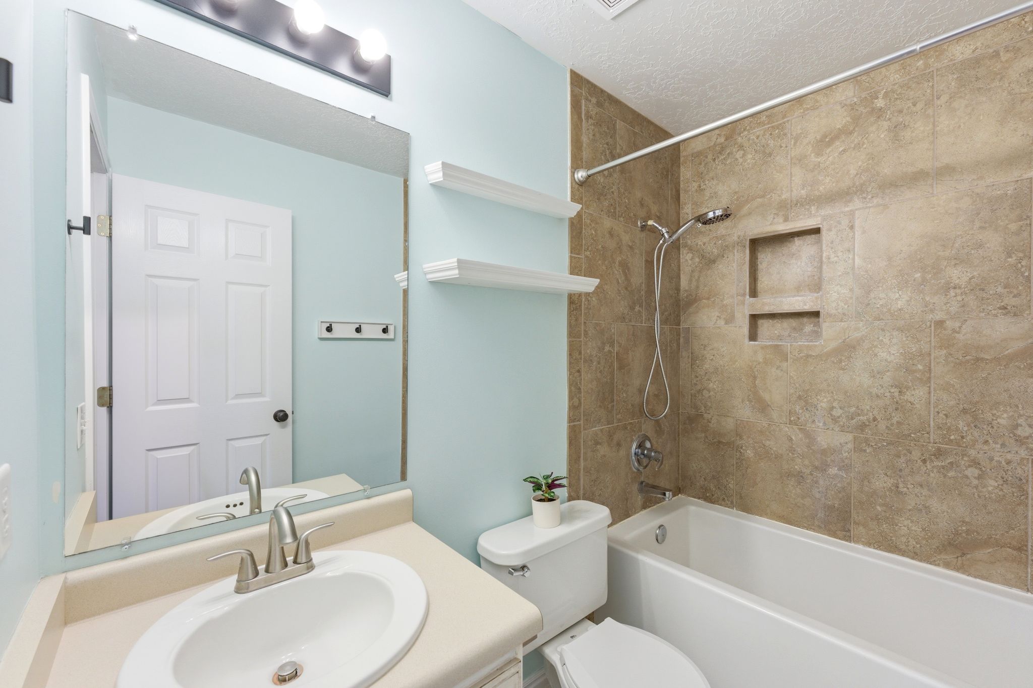 Bathroom featuring a white vanity with an oval undermount sink, brushed nickel faucet, and light-colored countertop