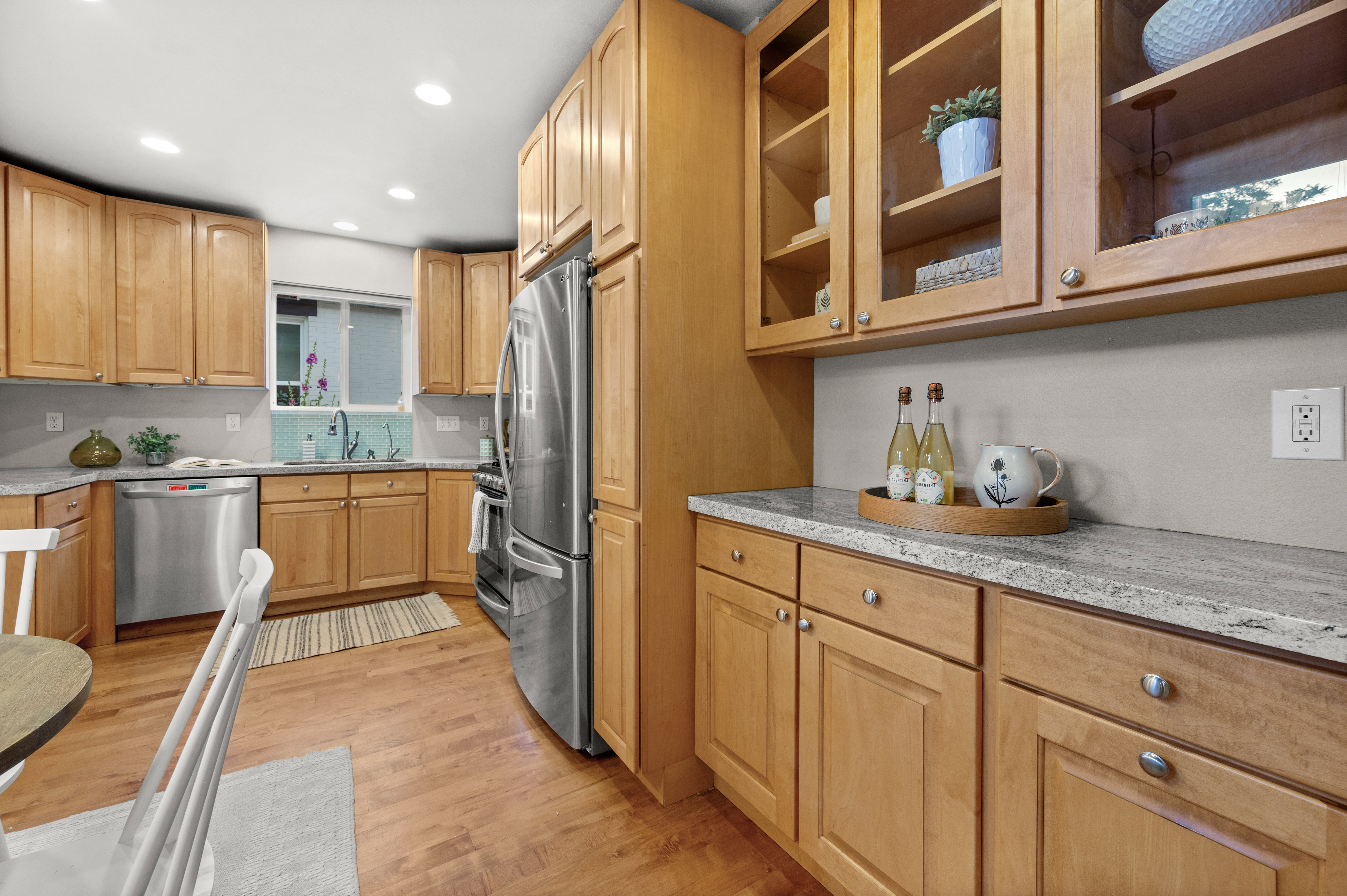Kitchen featuring natural wood cabinetry, stainless steel appliances, light gray countertops, and wood-finish flooring
