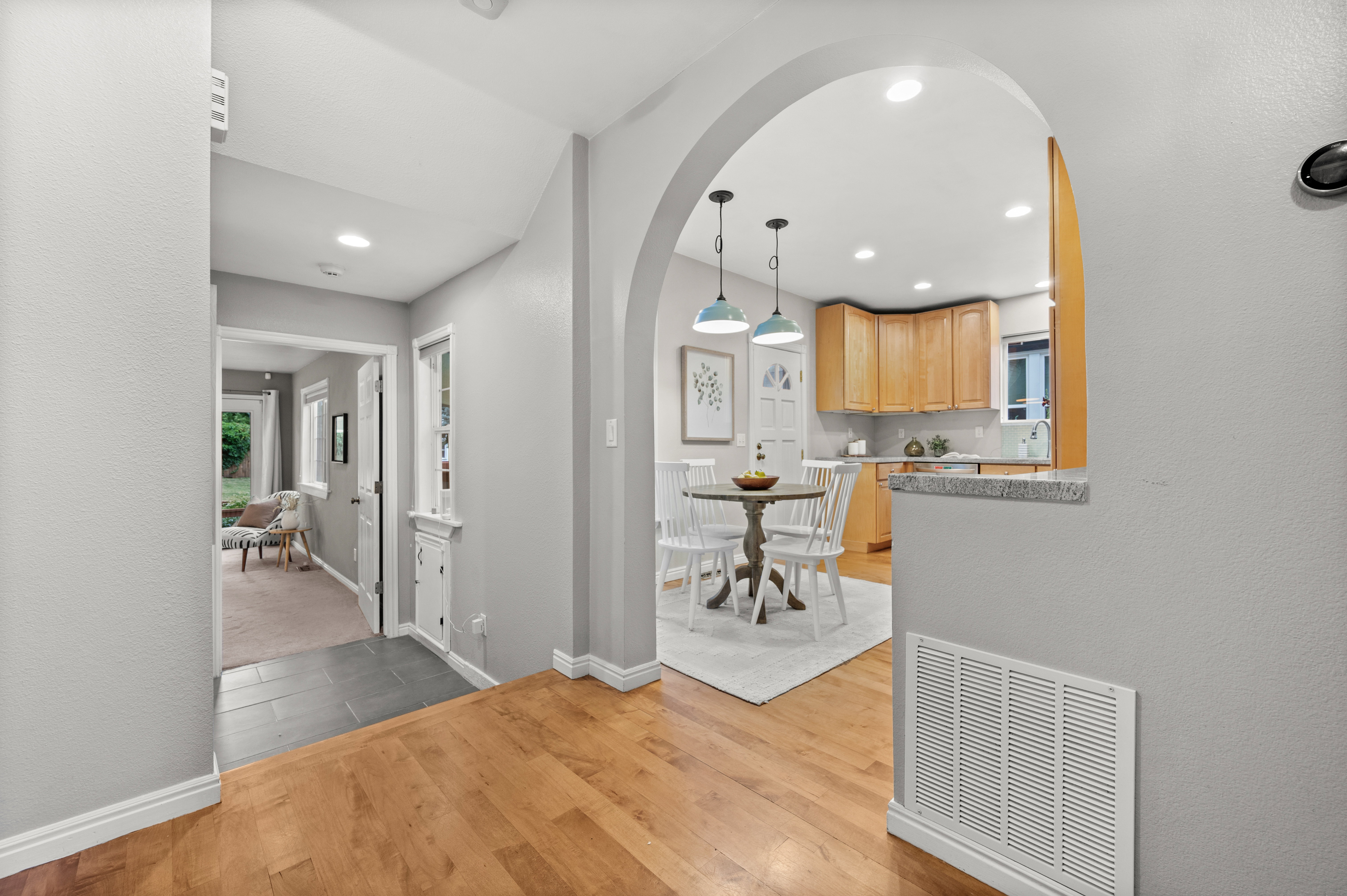Arched entryway providing access to a kitchen with wood cabinetry and a stone countertop