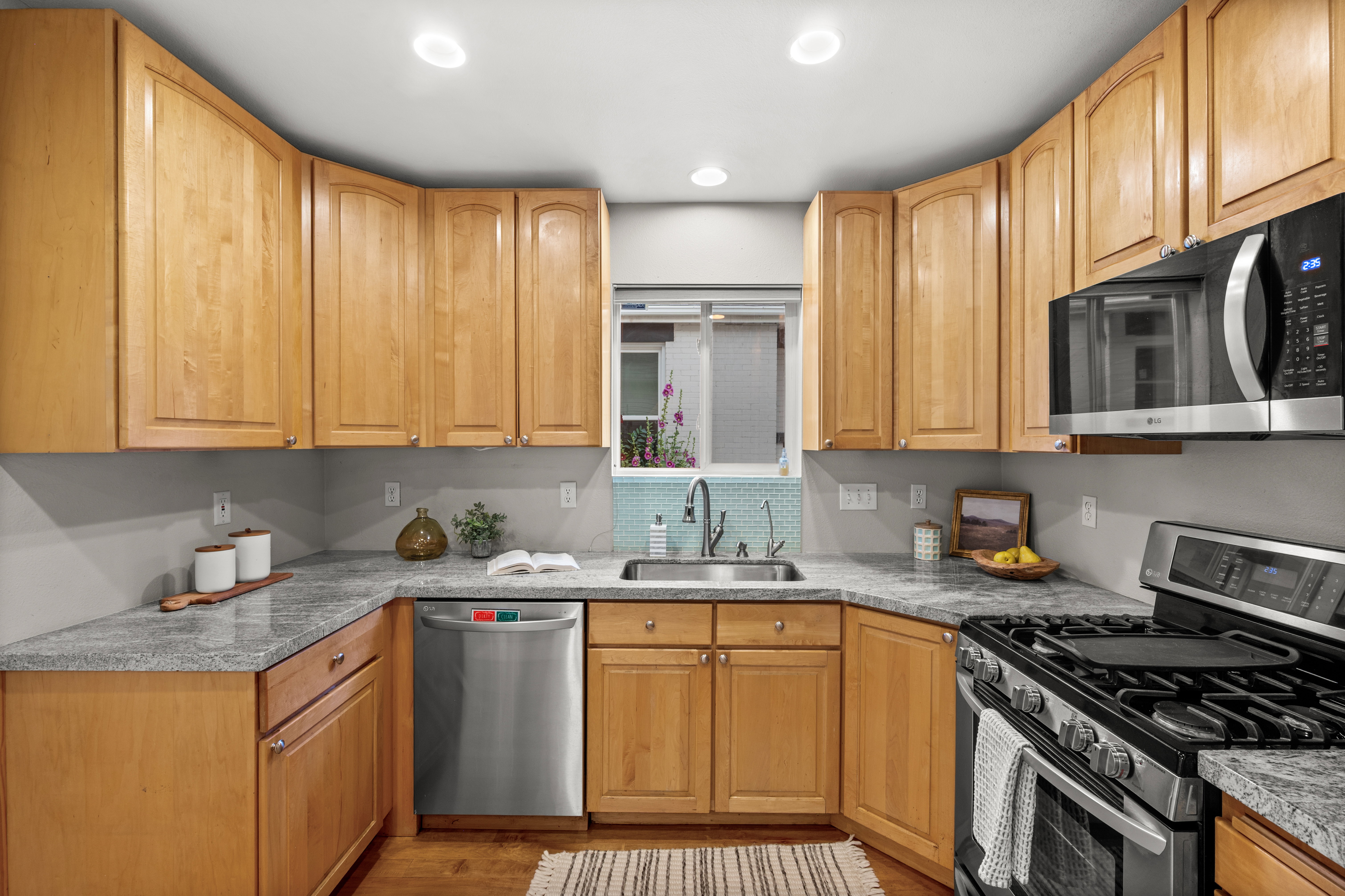 Kitchen featuring warm wood cabinetry, stone countertops, stainless steel appliances, a tile backsplash, and recessed lighting