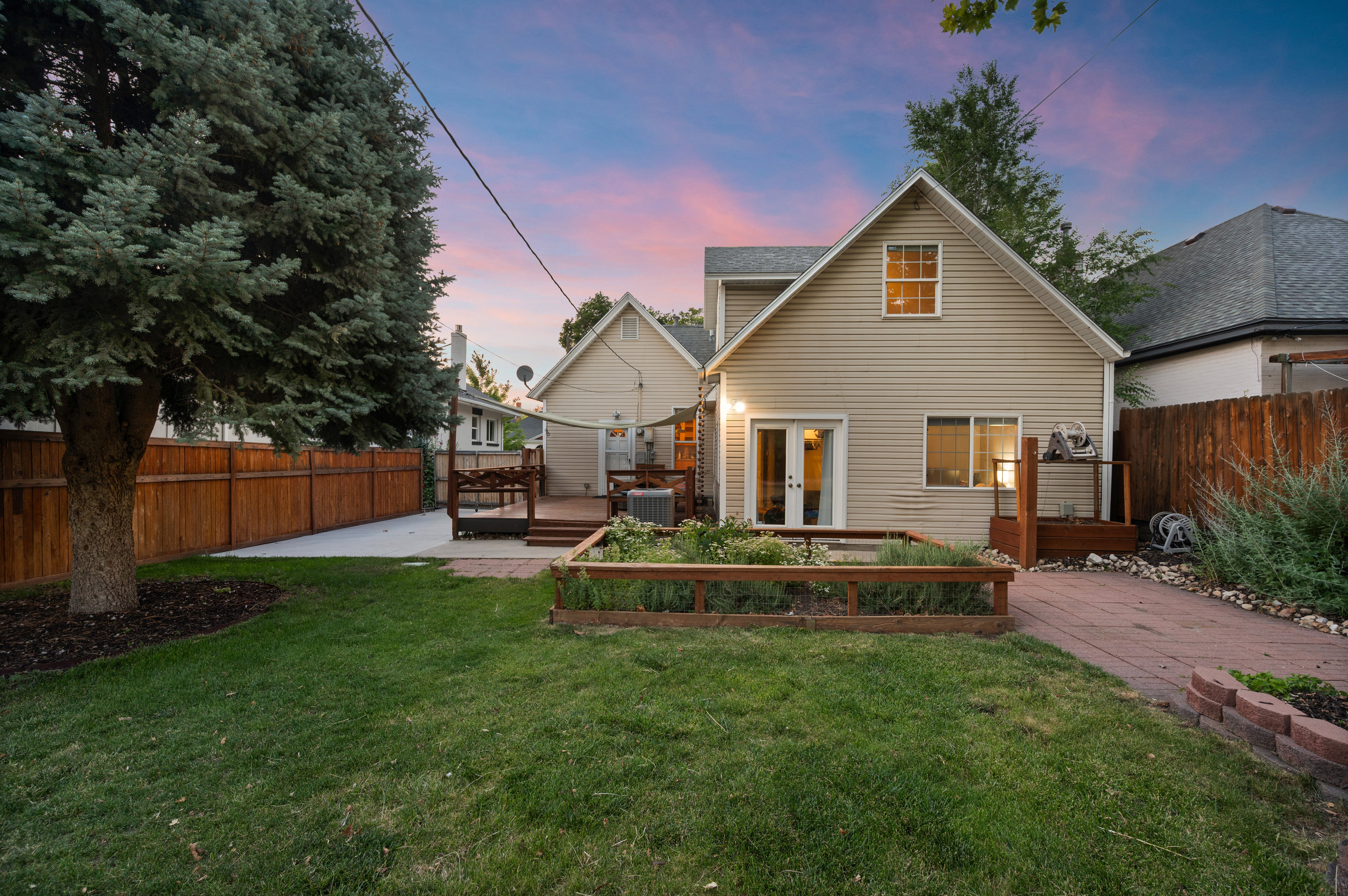 Expansive backyard featuring a manicured lawn, established landscaping, and a wood privacy fence