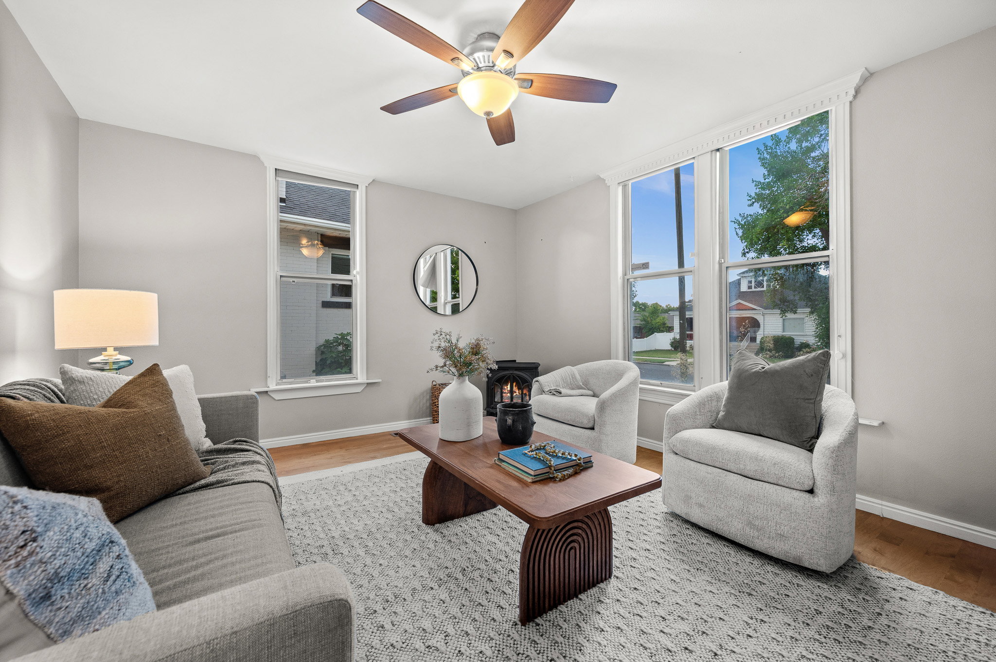Living area featuring wood-finish flooring, light grey wall paint, and a ceiling fan with integrated lighting