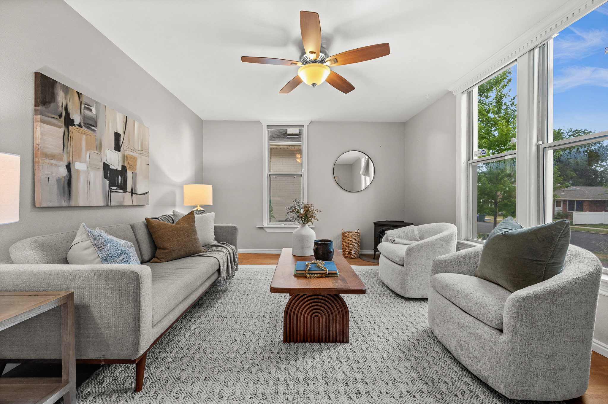 Living area featuring light gray walls, wood-finish flooring, and a ceiling fan