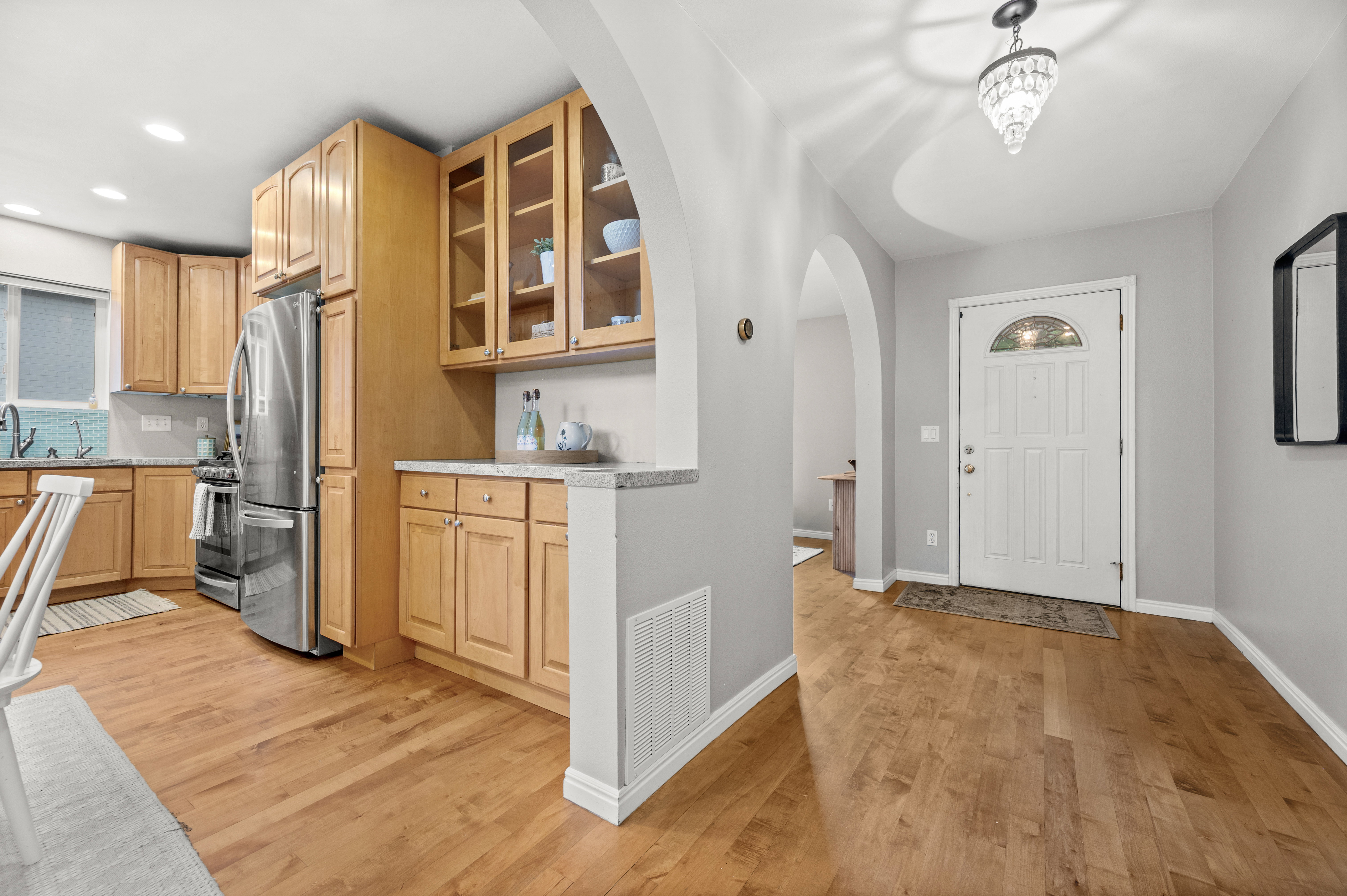 Entryway featuring a white paneled door with arched transom, wood-finish flooring, and a crystal chandelier