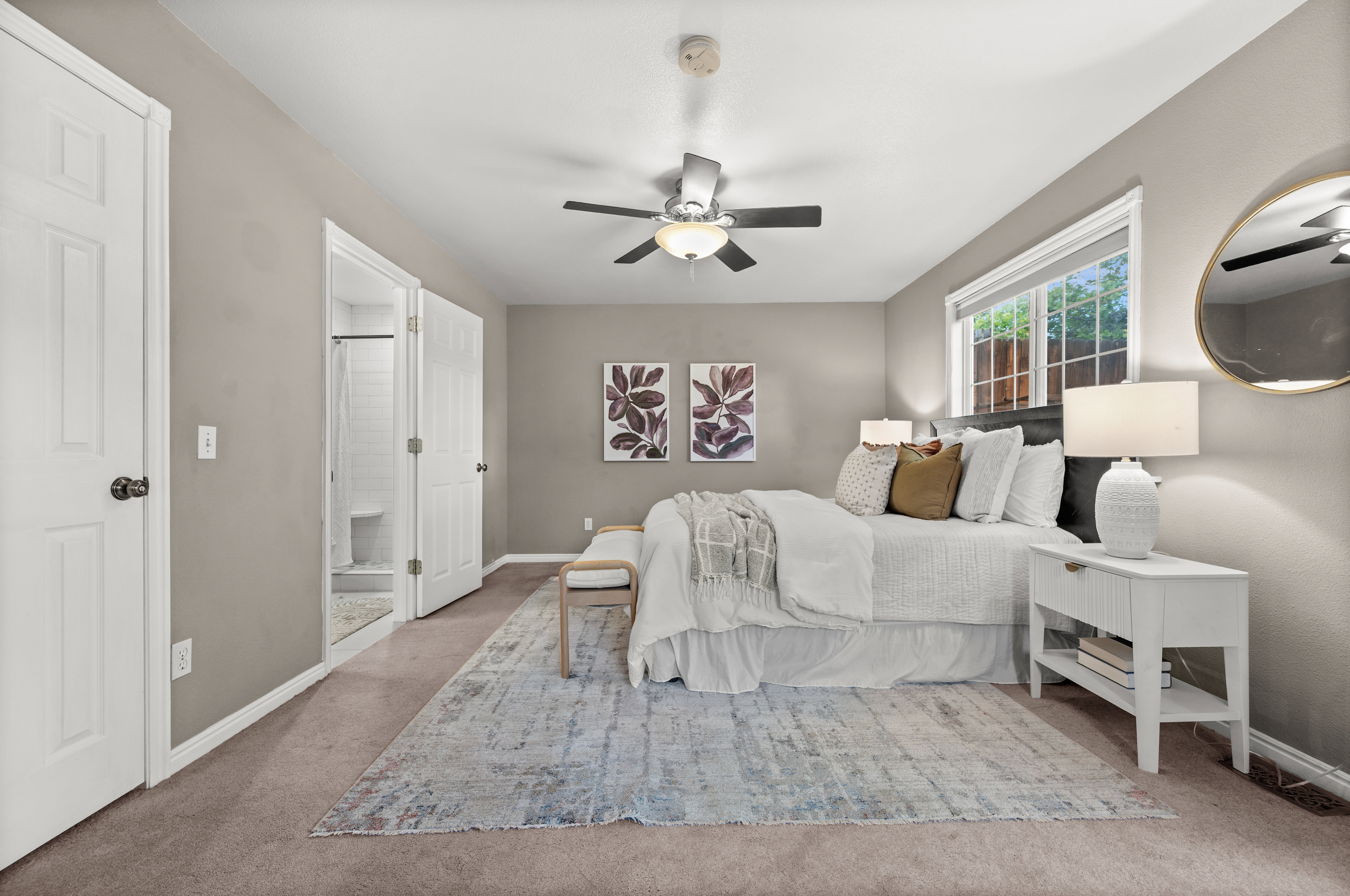 Carpeted room with a ceiling fan, a window, and an en-suite bathroom with a tiled shower