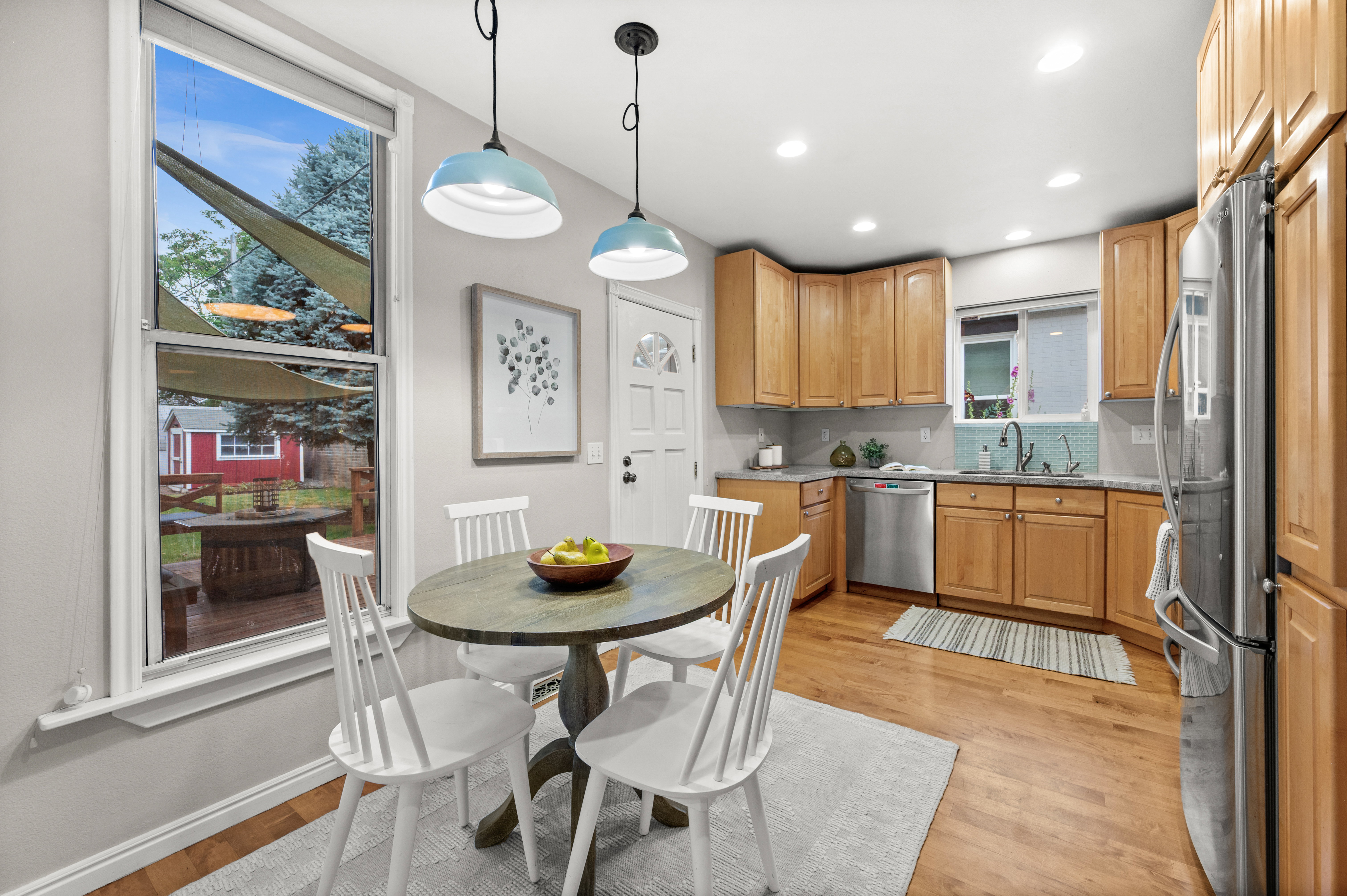 Kitchen and dining area featuring wood-finish flooring, two pendant lights, recessed lighting, and a white paneled door