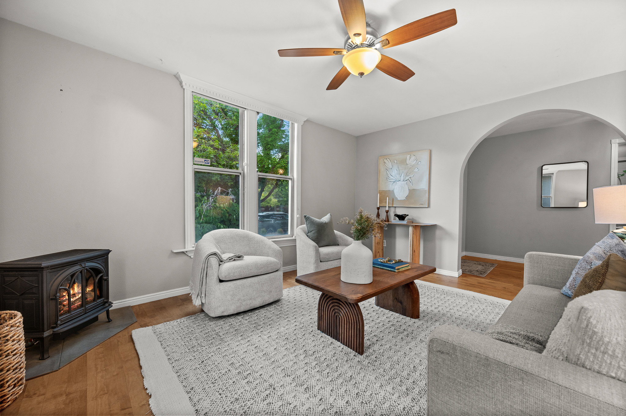 Living area featuring wood-finish flooring, a ceiling fan with light, and an arched entryway