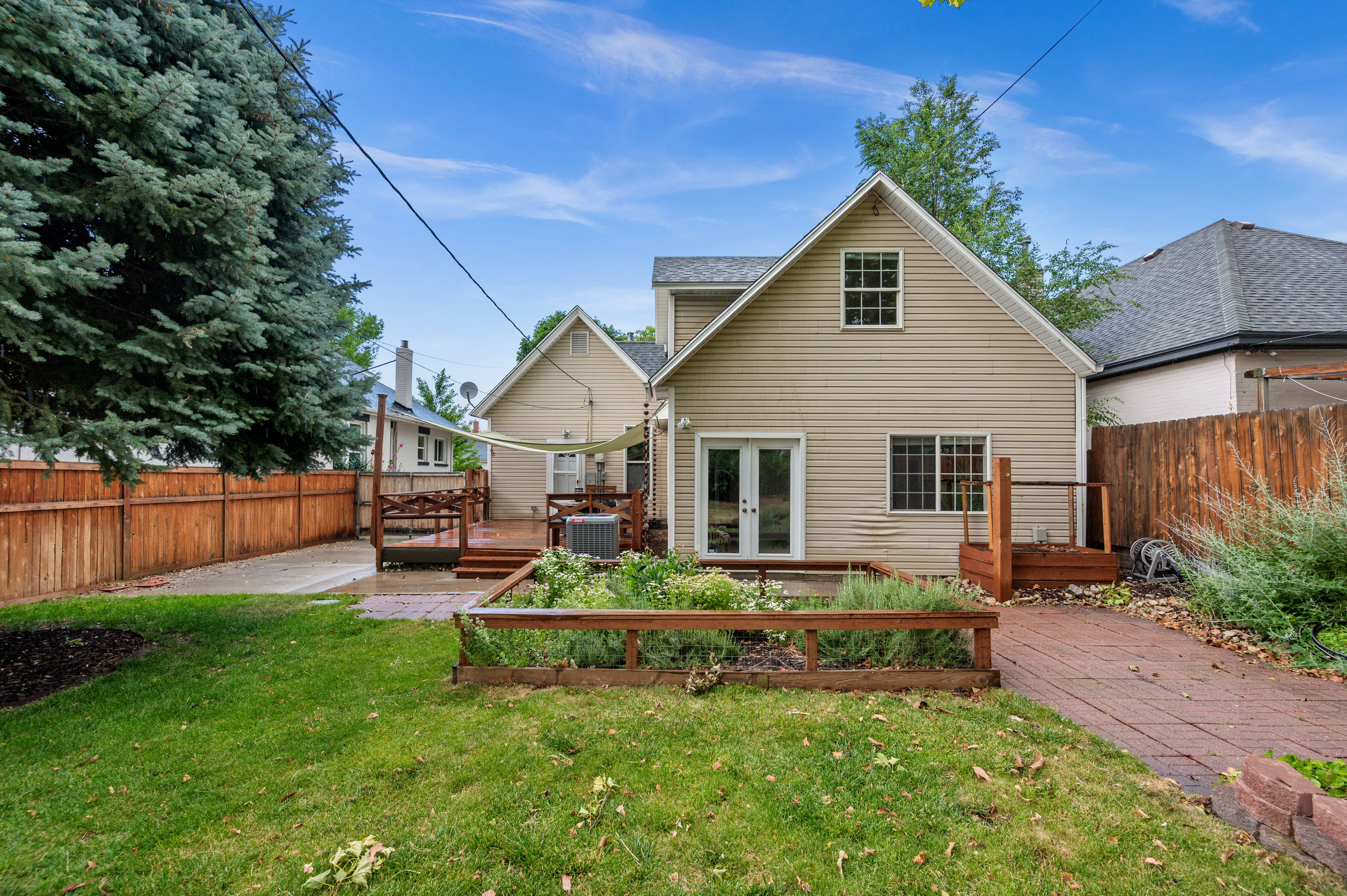 Expansive backyard featuring a manicured lawn, a raised garden bed, and a paved walkway