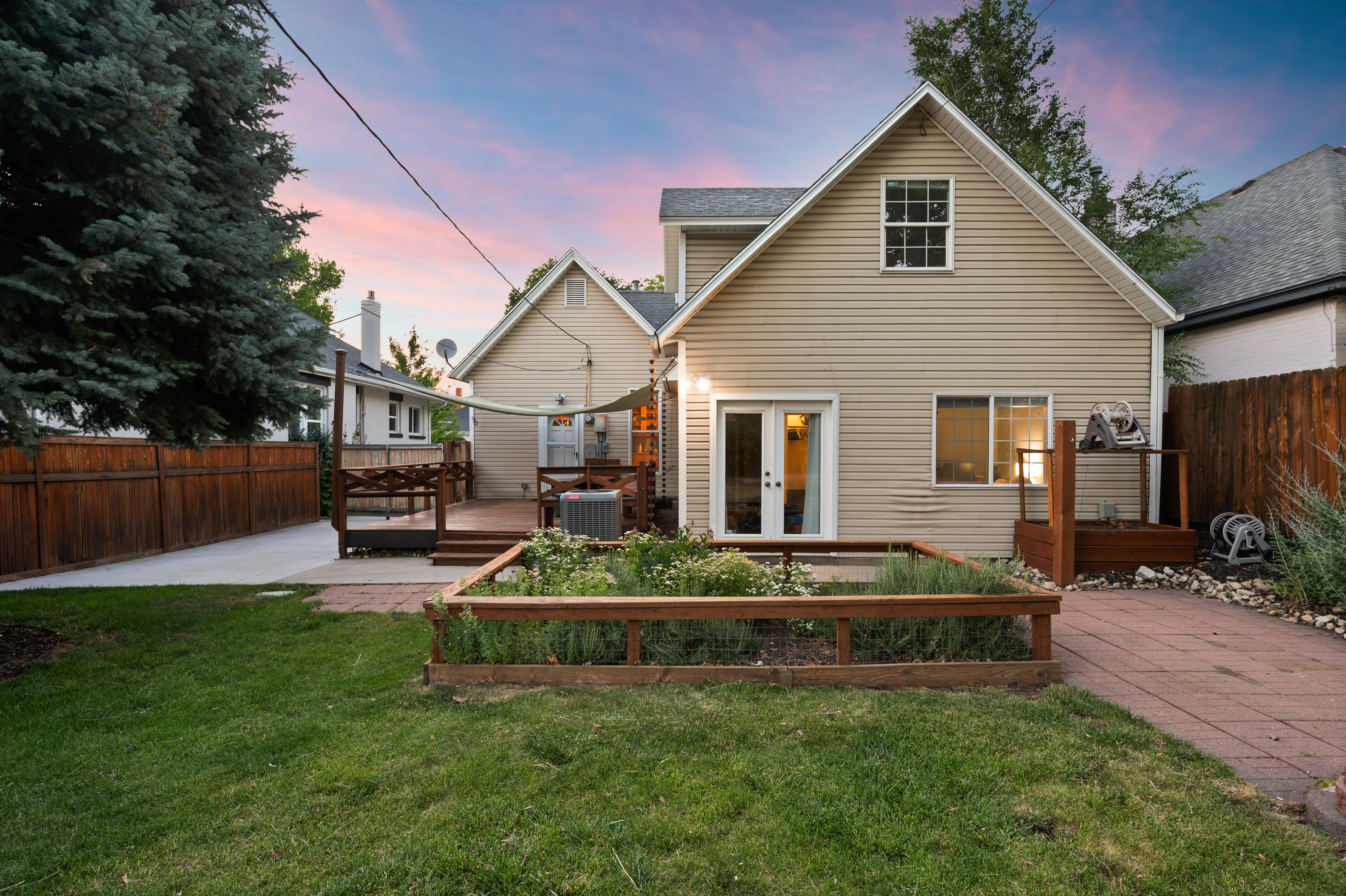 Expansive backyard featuring a manicured lawn, a raised garden bed with wood framing, and a paver patio with a stone border