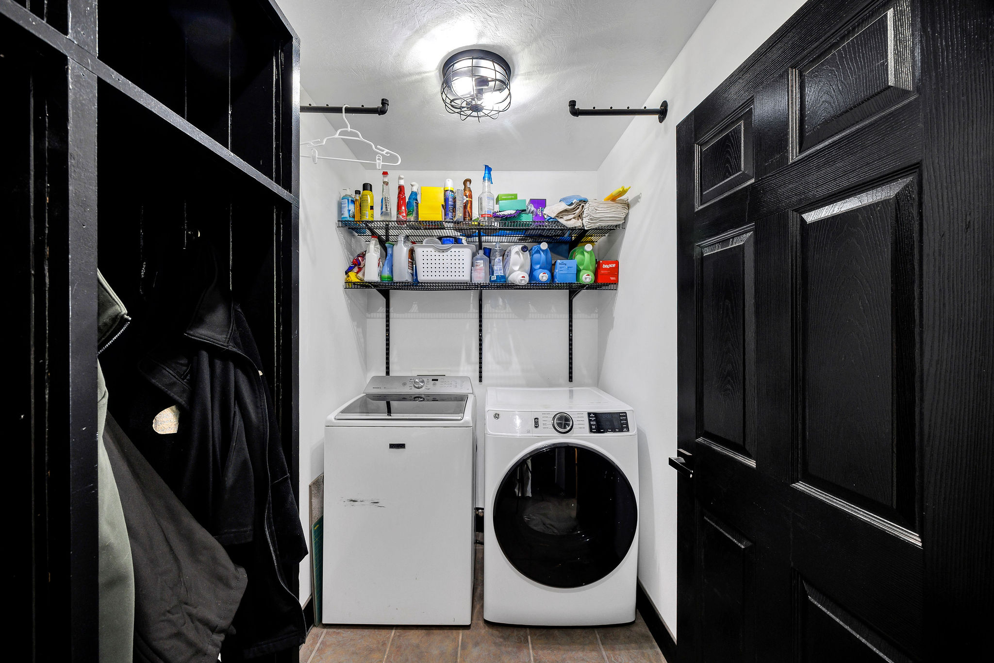 Dedicated laundry space featuring tile flooring and overhead shelving