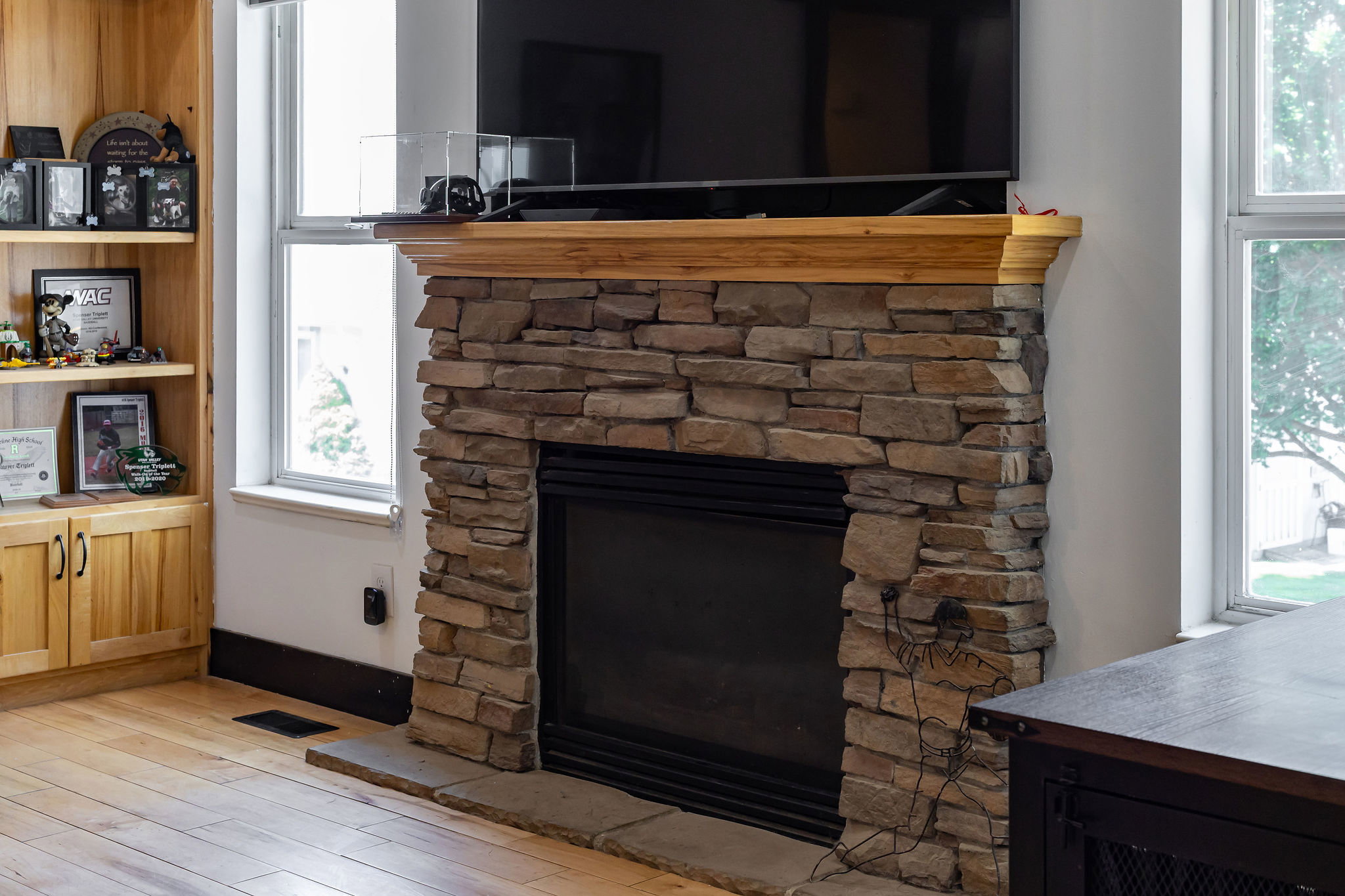 Stacked stone fireplace with a wood-finish mantel and hearth