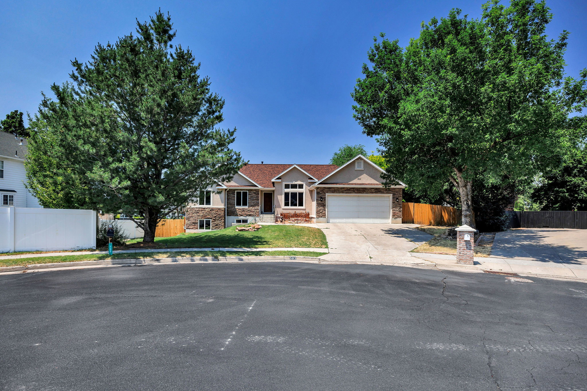 Single-story residence featuring a two-car garage, stone and stucco exterior, and a gabled roof