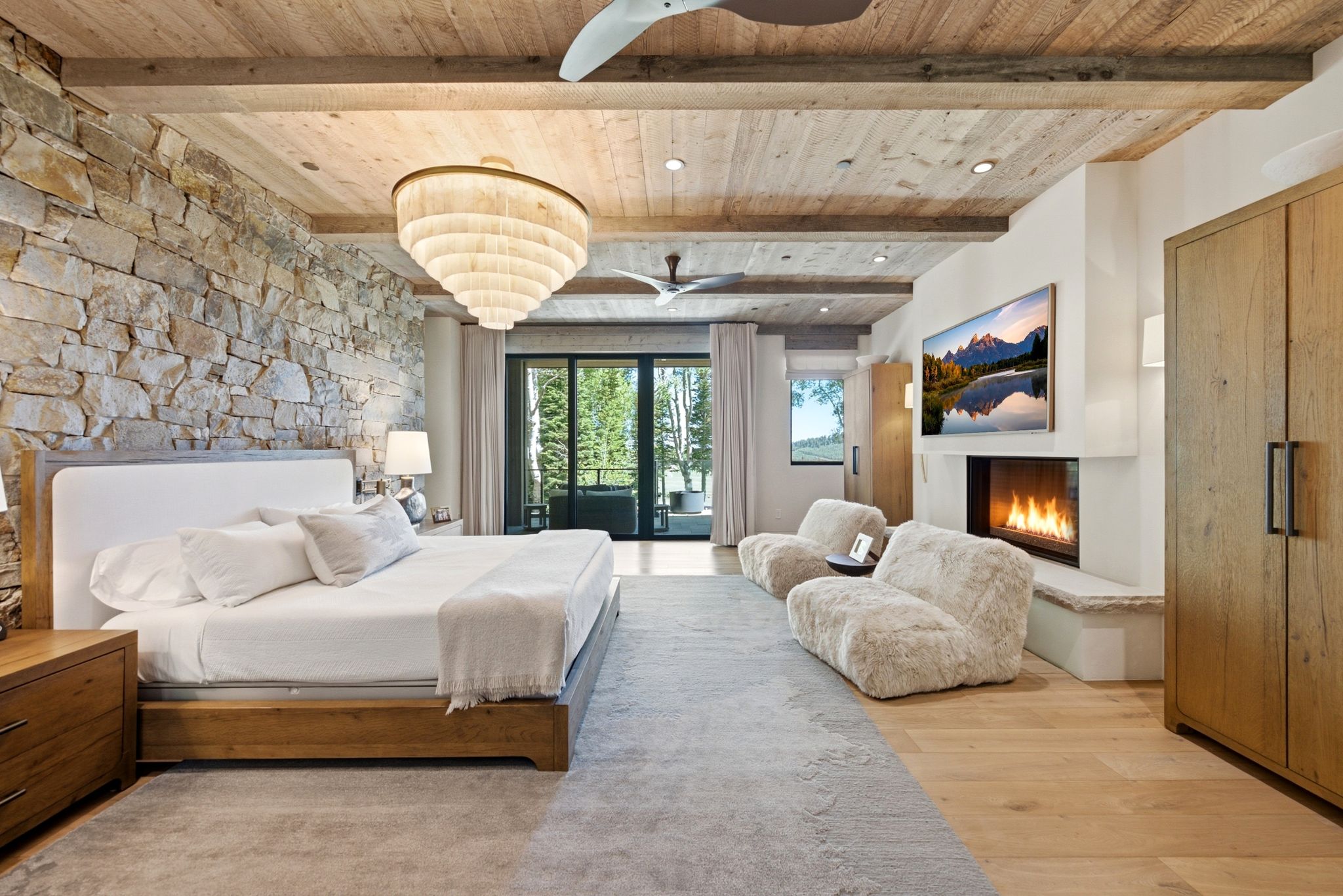 Expansive interior featuring a stone accent wall, wood-finish ceiling with exposed beams, built-in fireplace, and sliding glass doors to the exterior