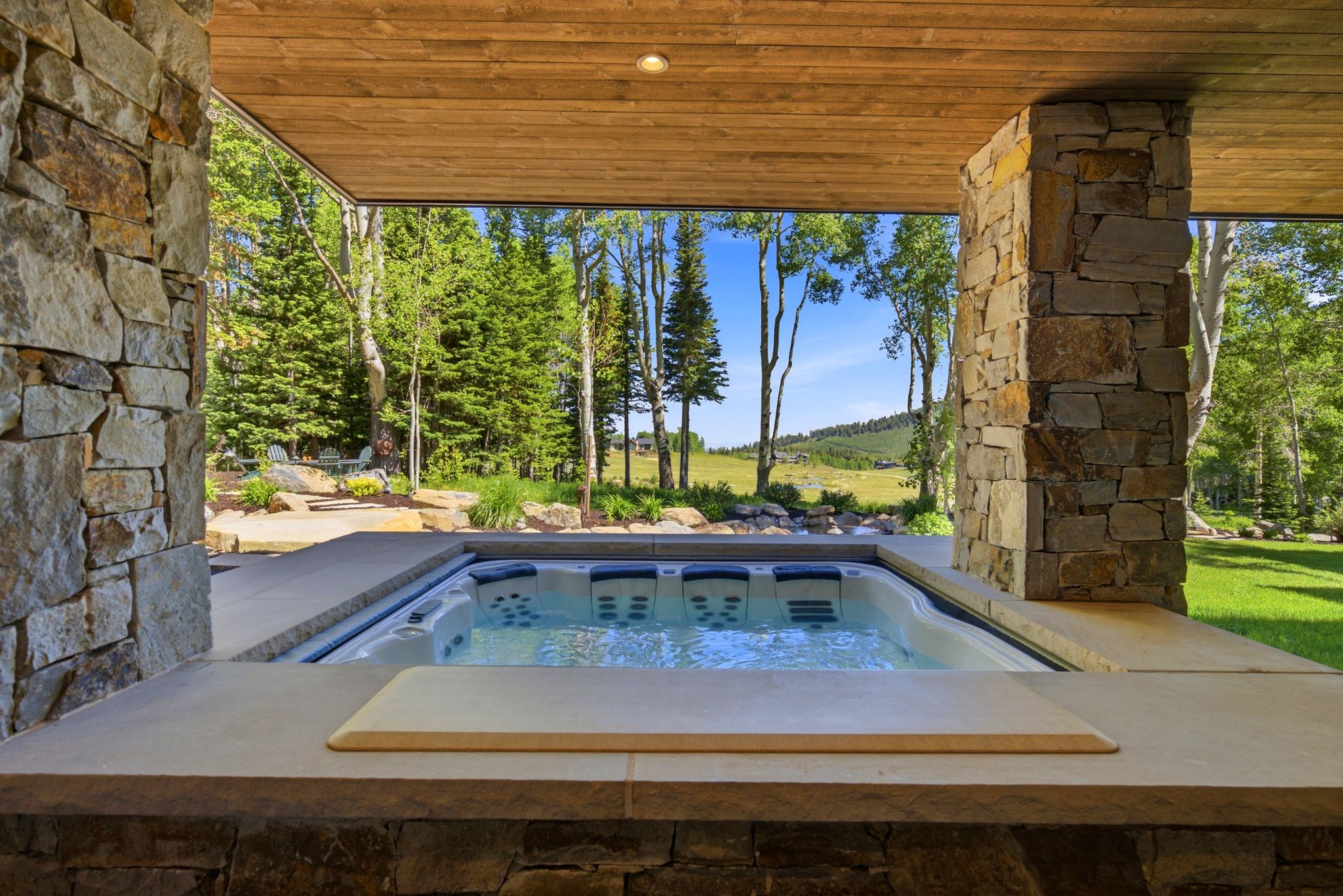 Built-in spa with integrated seating framed by stone columns and a wood-paneled ceiling