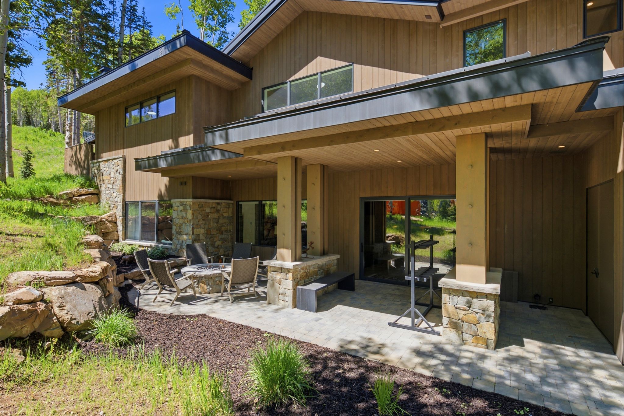 Expansive outdoor patio featuring paver flooring, stone pillars, and a wood-paneled ceiling