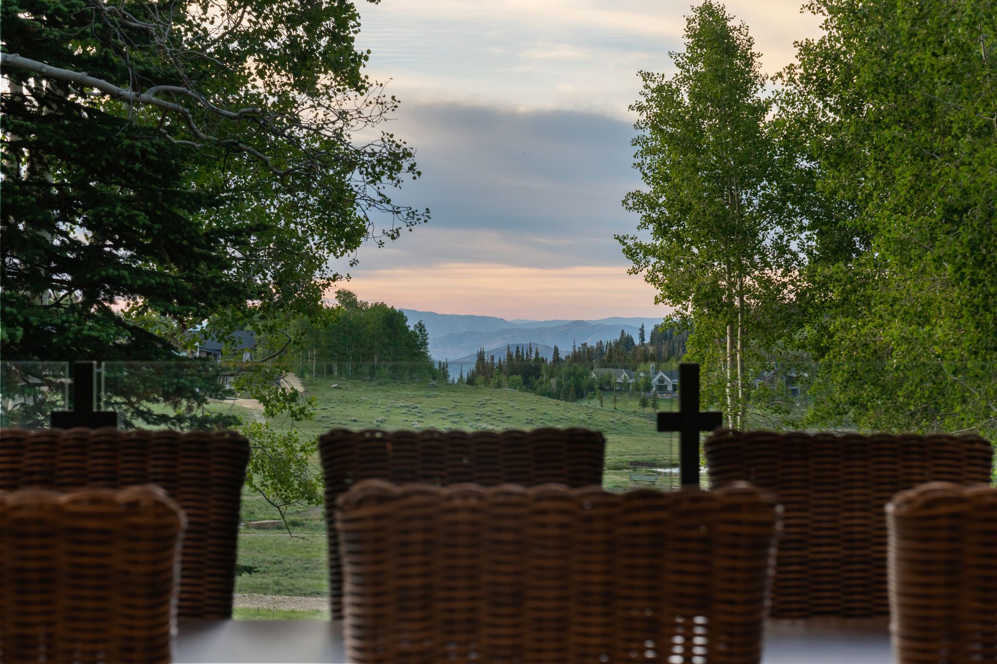 Expansive outdoor living area featuring a clear glass railing and a forested mountainous backdrop