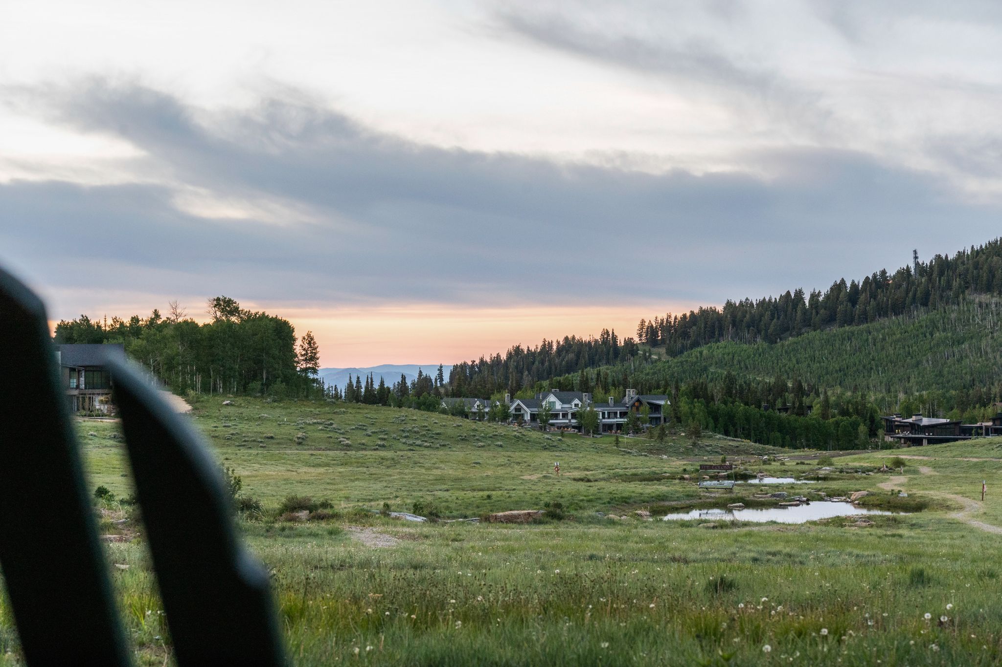 Expansive natural landscape featuring rolling grassy terrain and distant residences