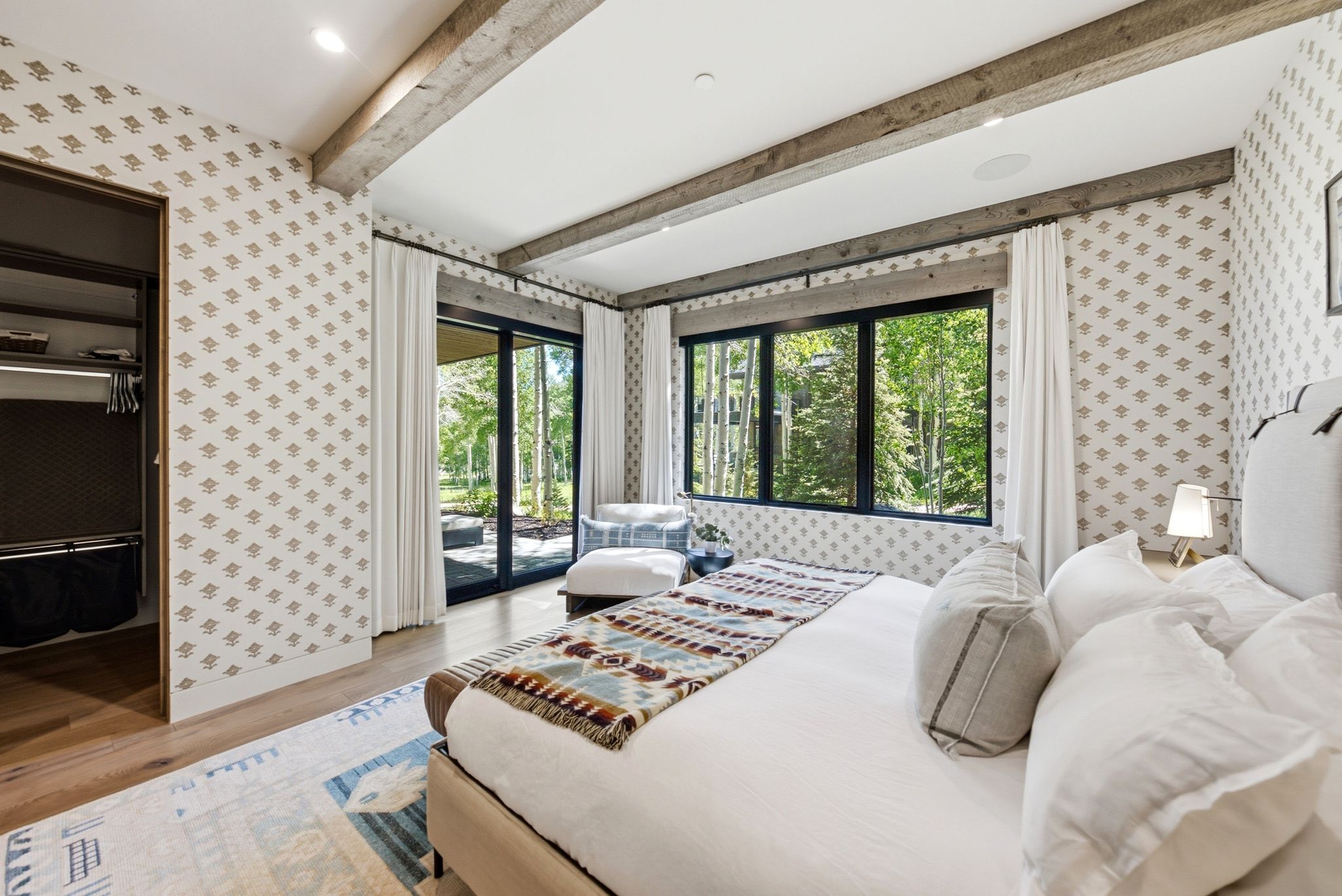 Spacious room featuring wood-finish flooring and patterned wallpaper