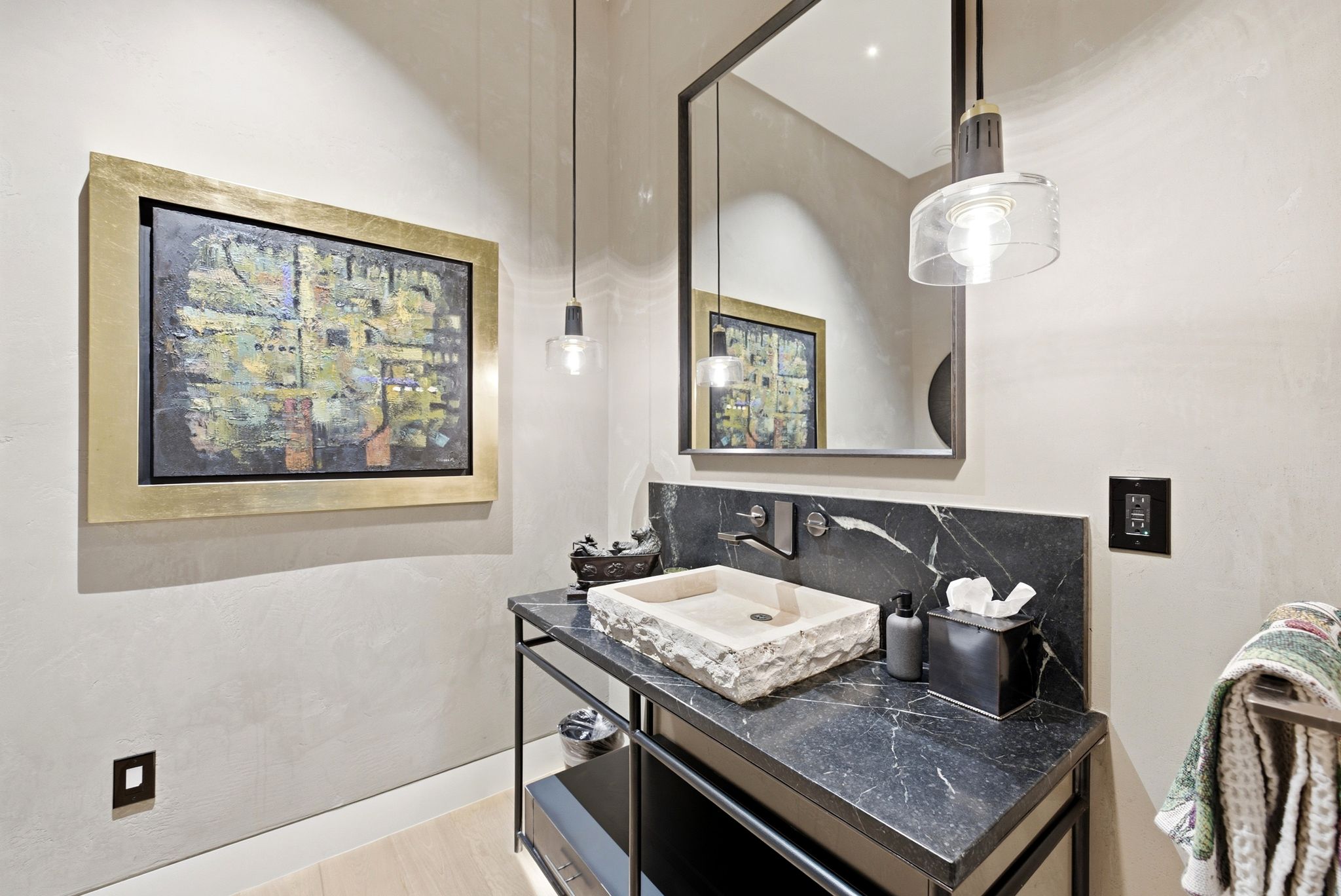 Vanity area featuring a rough-hewn vessel sink, black stone countertop, and wall-mounted faucet