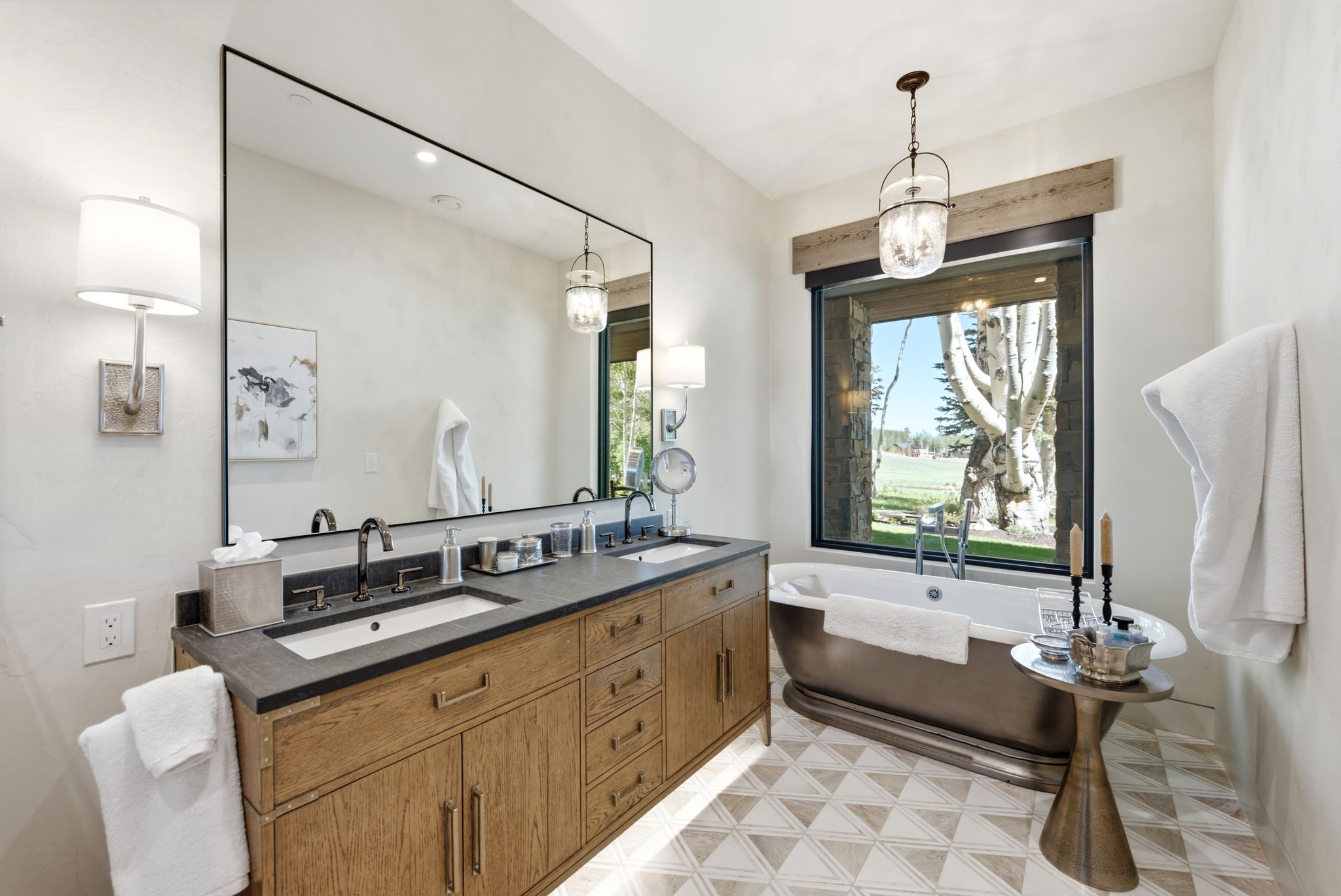 Bathroom featuring a freestanding tub, wood-finish double vanity with dual sinks, and a large window