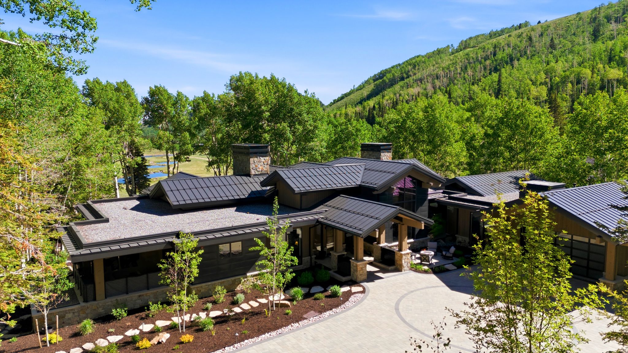 Contemporary architecture with multiple rooflines, stone and wood-paneled exterior, and an integrated garage