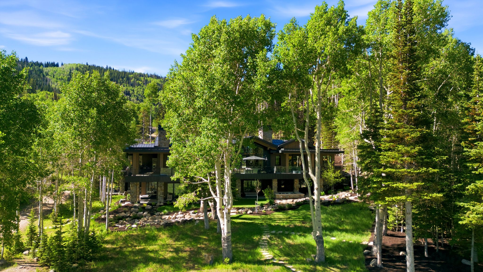 Contemporary mountain residence featuring multiple levels, stone veneer accents, and glass railings on balconies