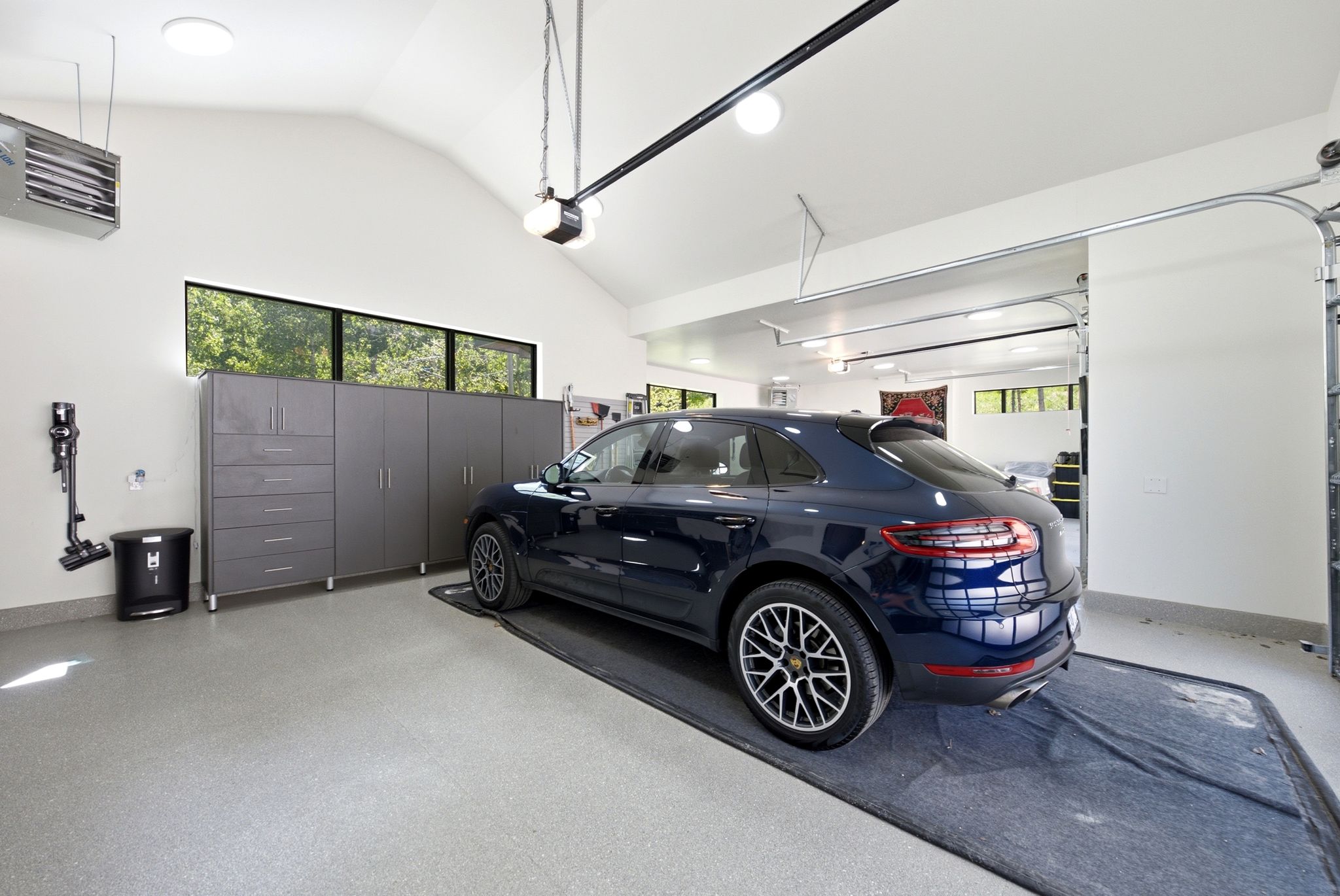 Spacious garage with light gray speckled flooring, vaulted ceilings, and a row of high-set horizontal windows