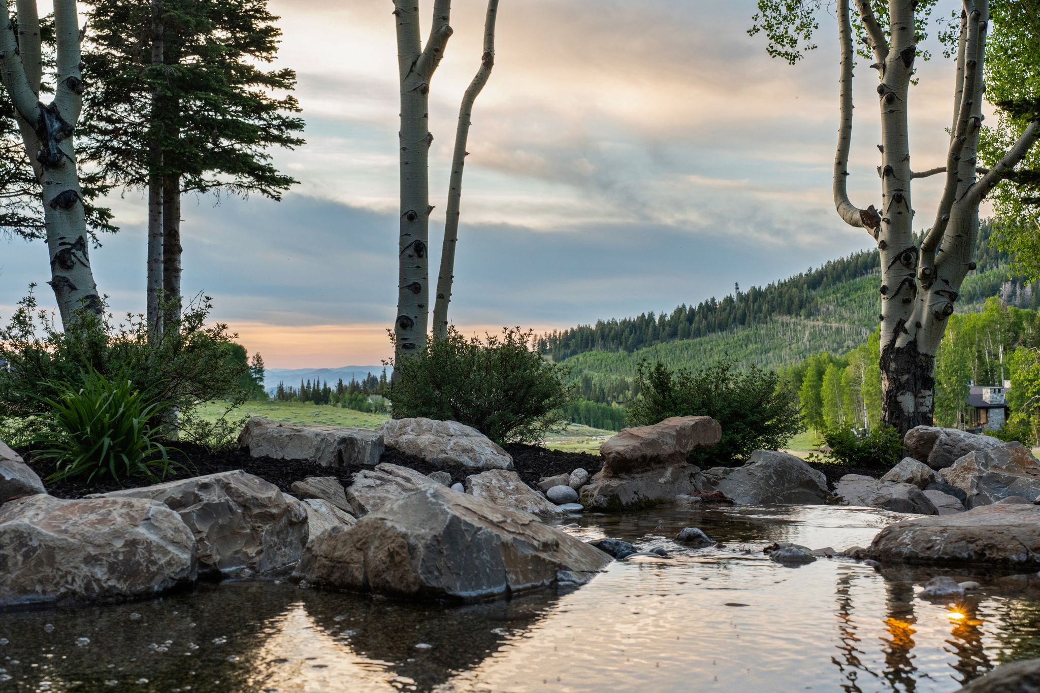 Water feature surrounded by natural stone boulders and mature trees