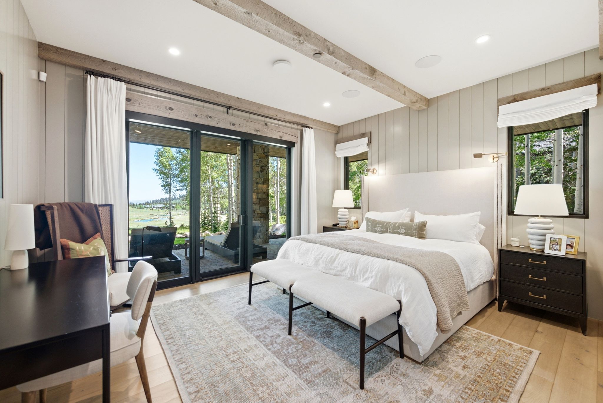 Spacious bedroom featuring light wood flooring and a paneled accent wall