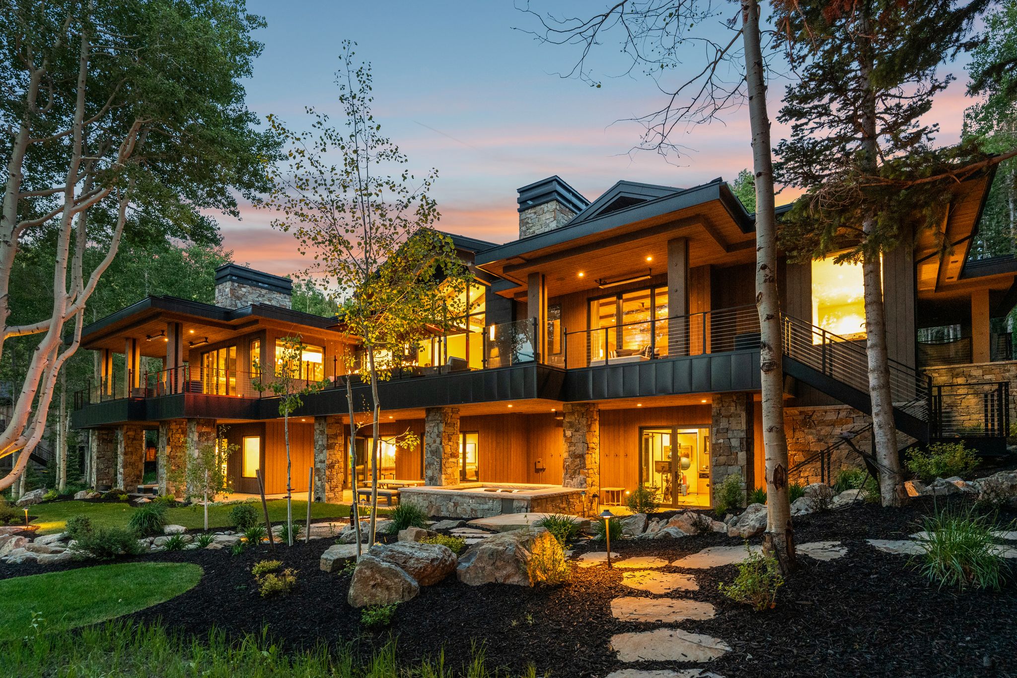 Modern mountain exterior featuring extensive stone detailing, wood siding, and large windows