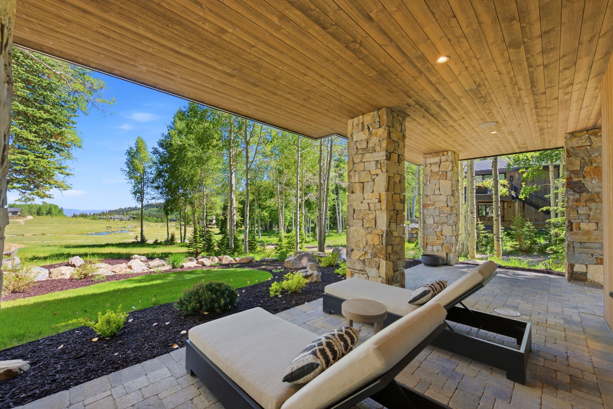 Covered outdoor patio featuring stone columns and wood-paneled ceiling